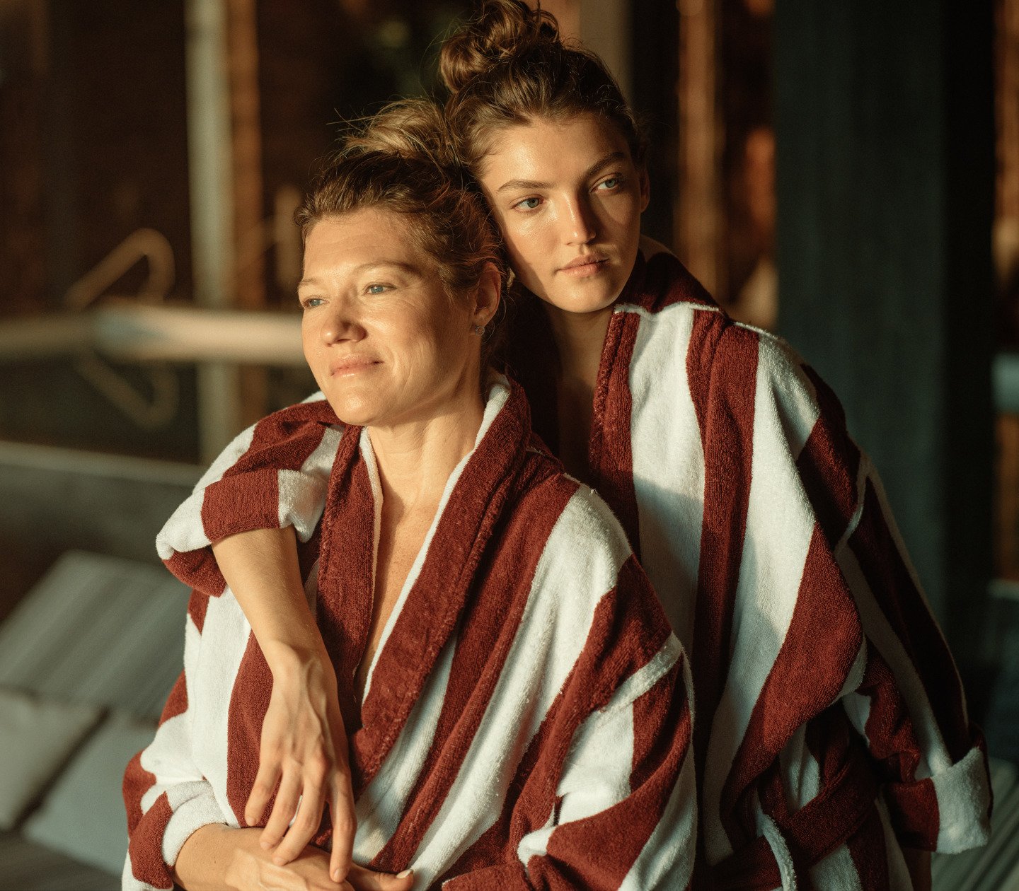 Mor och dotter som kramas i randiga badrockar 