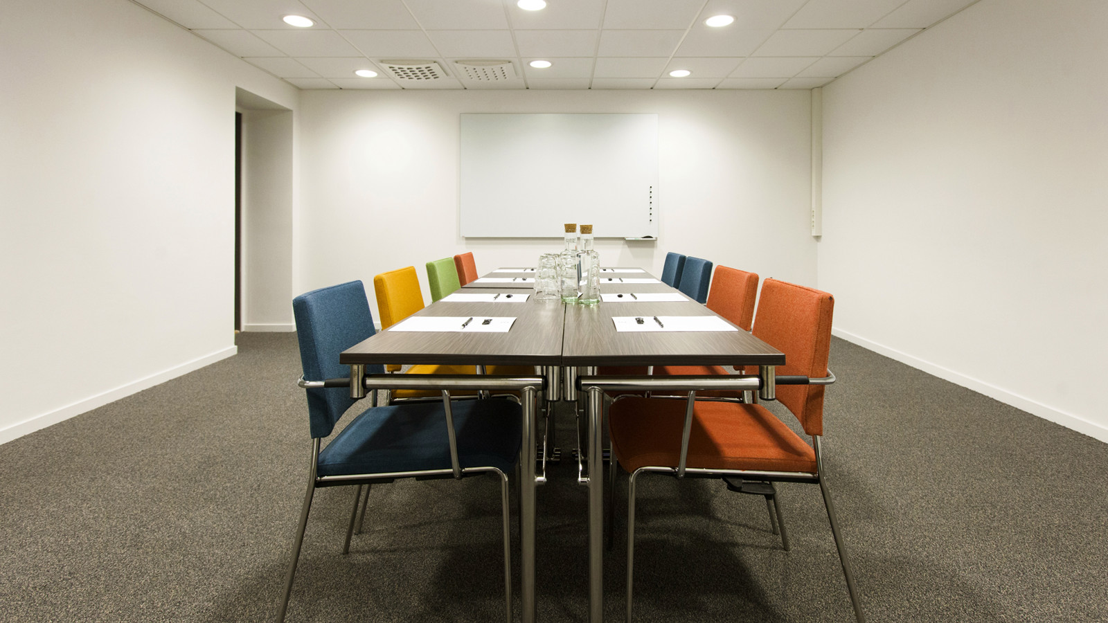White conference room with table and colourful chairs