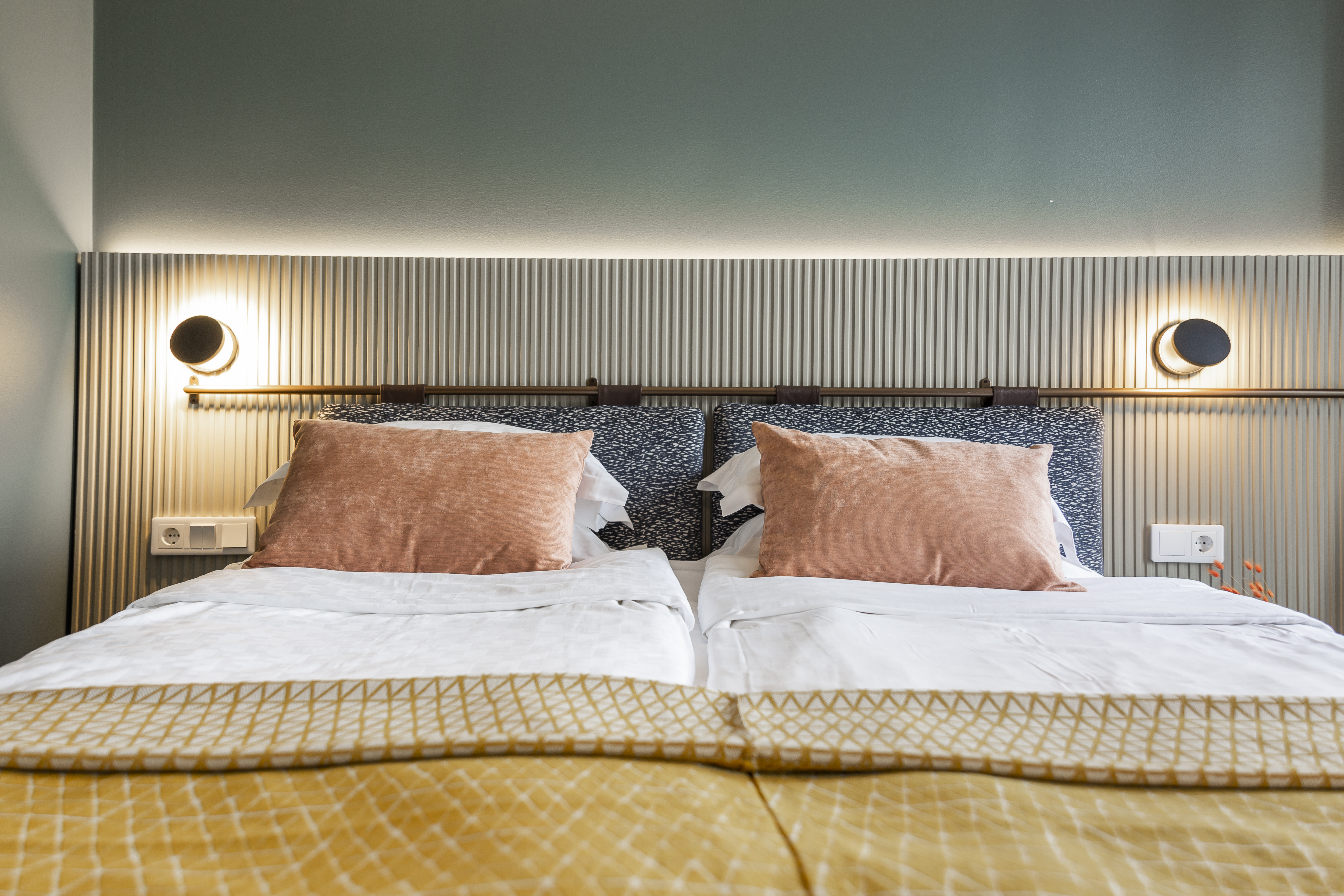Ombonat hotellrum med dubbelsäng, varma textiler och sänglampor
