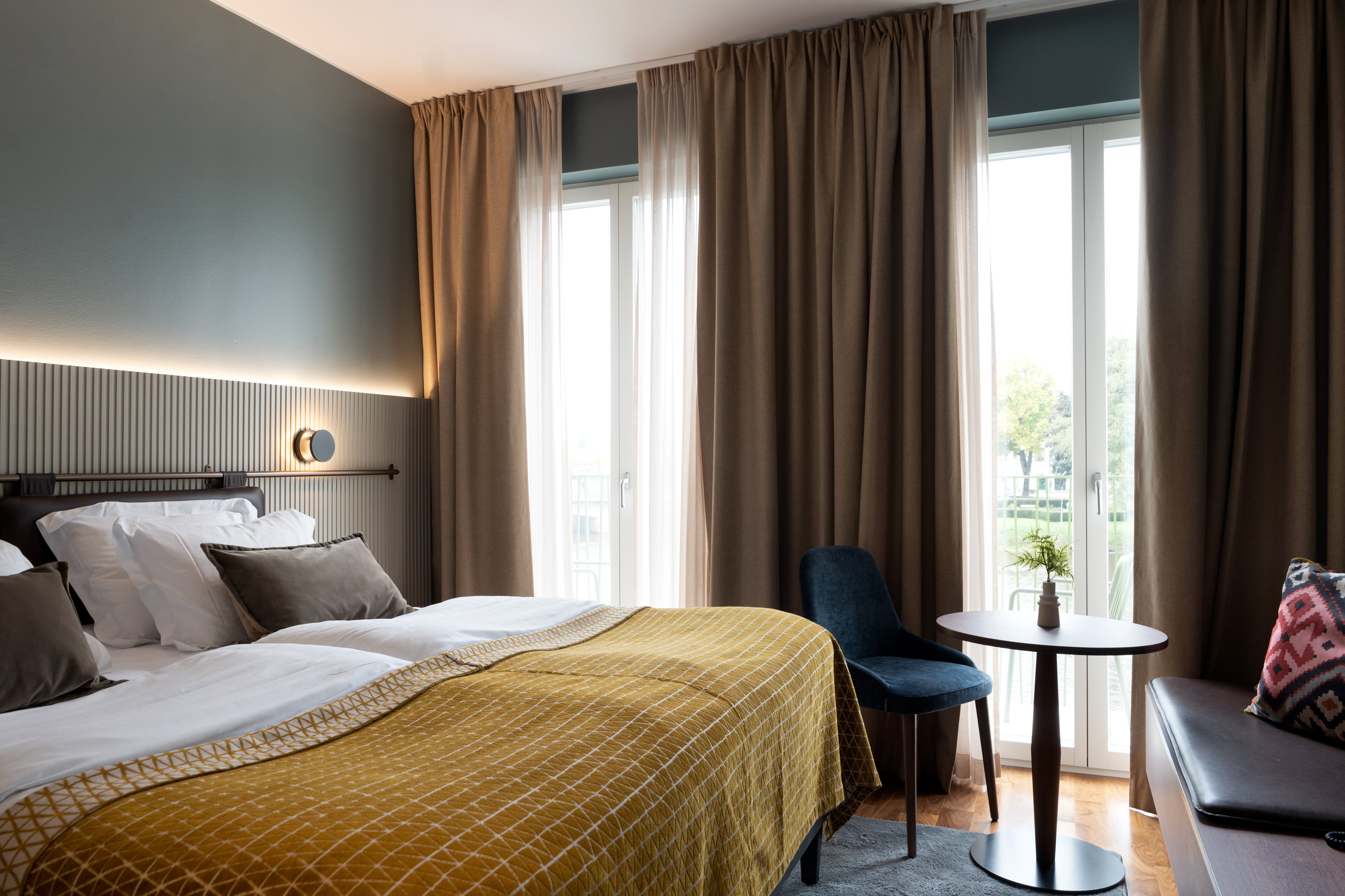 Ombonat hotellrum med dubbelsäng, varma textiler och stora fönster