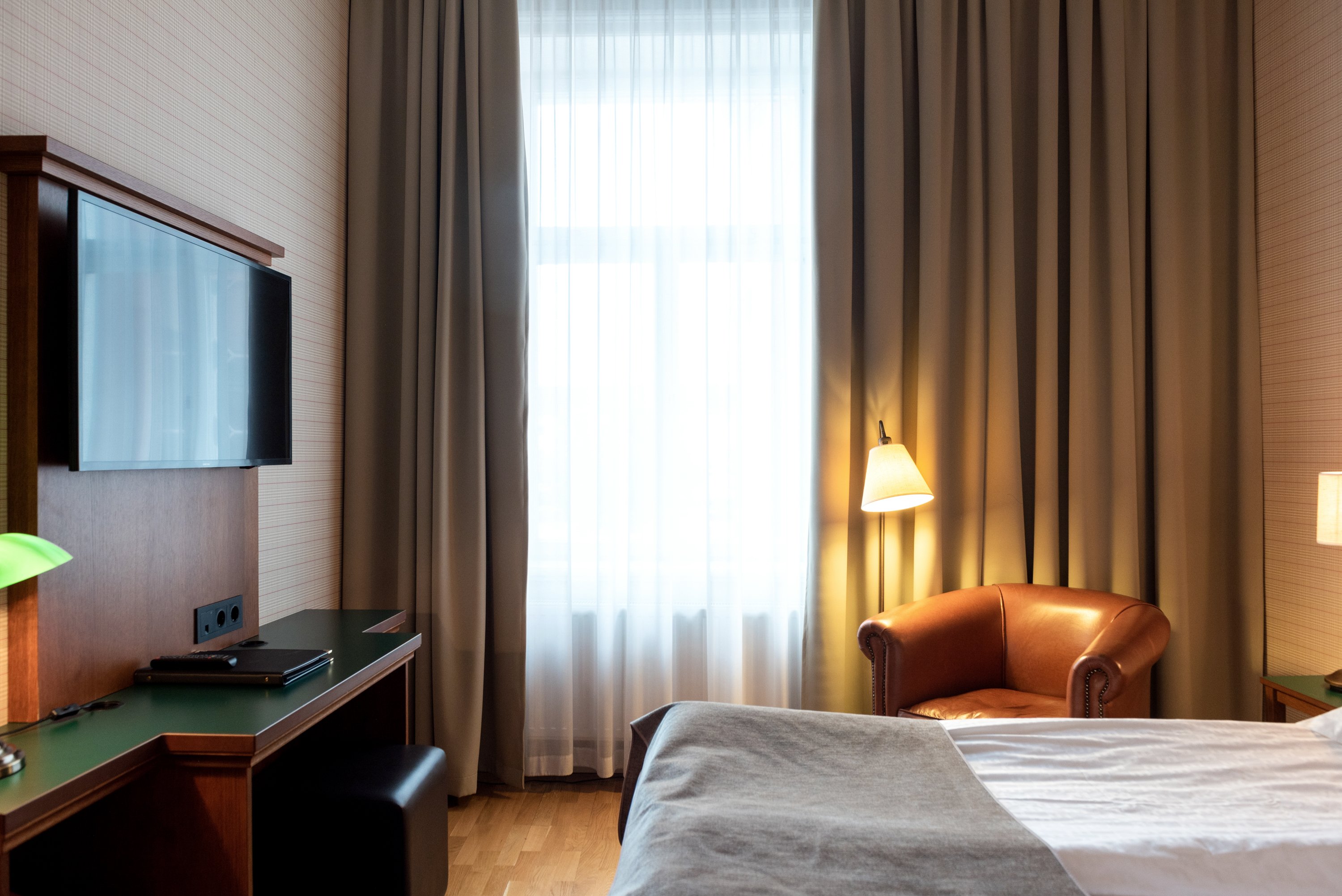 Hotellrum med säng, läderfåtölj och tv