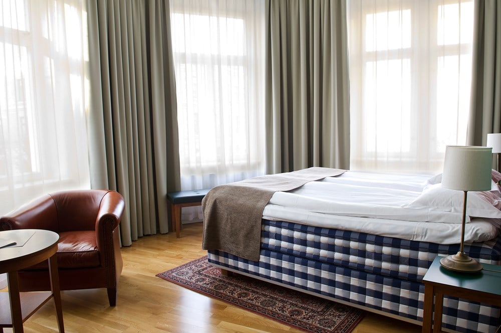 Hotellrum med Hästens-säng, läderfåtölj och fönster