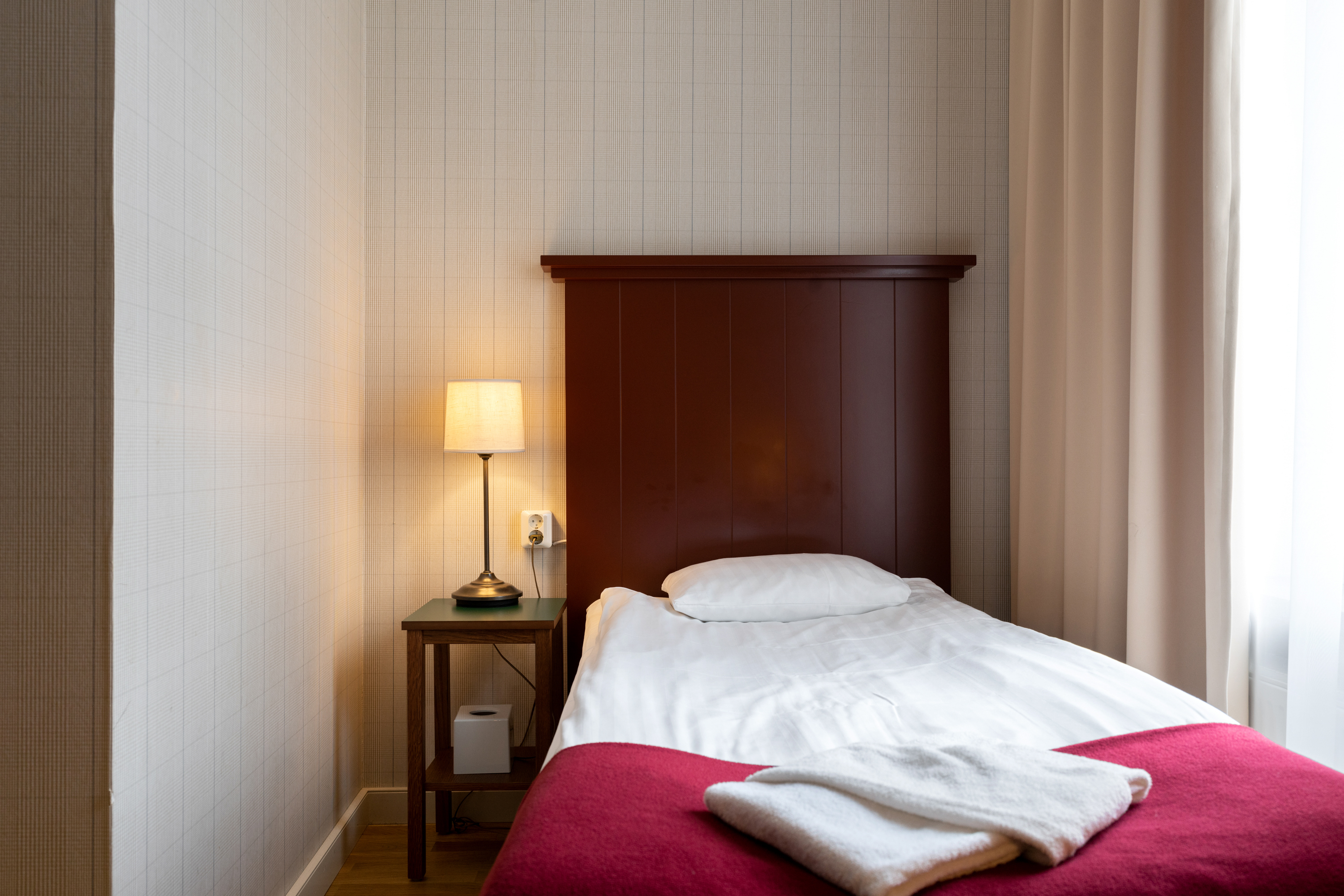 Mysigt hotellrum med säng, sänggavel i trä och sänglampa