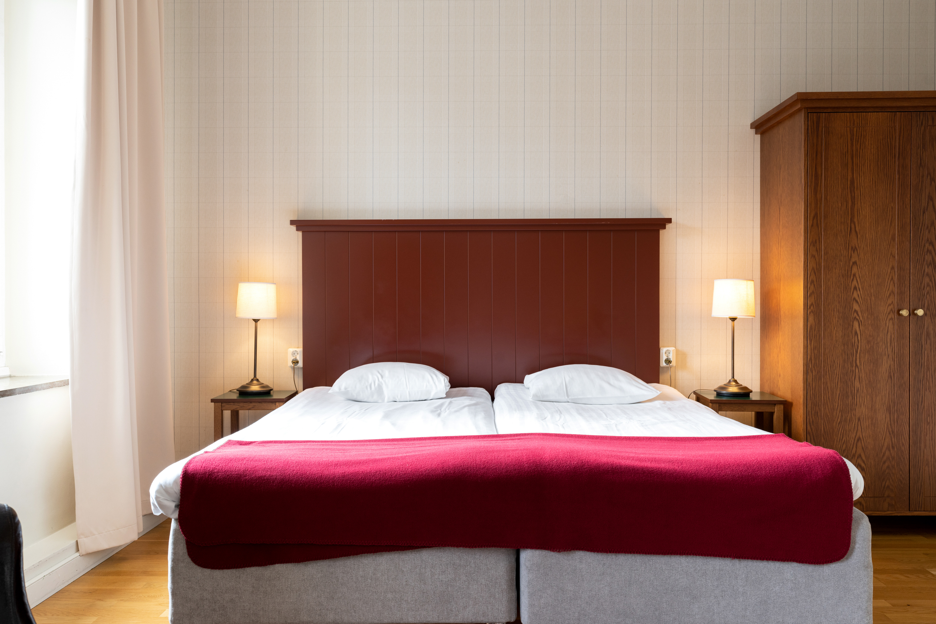 Mysigt hotellrum med säng, sänggavel i trä och sänglampor