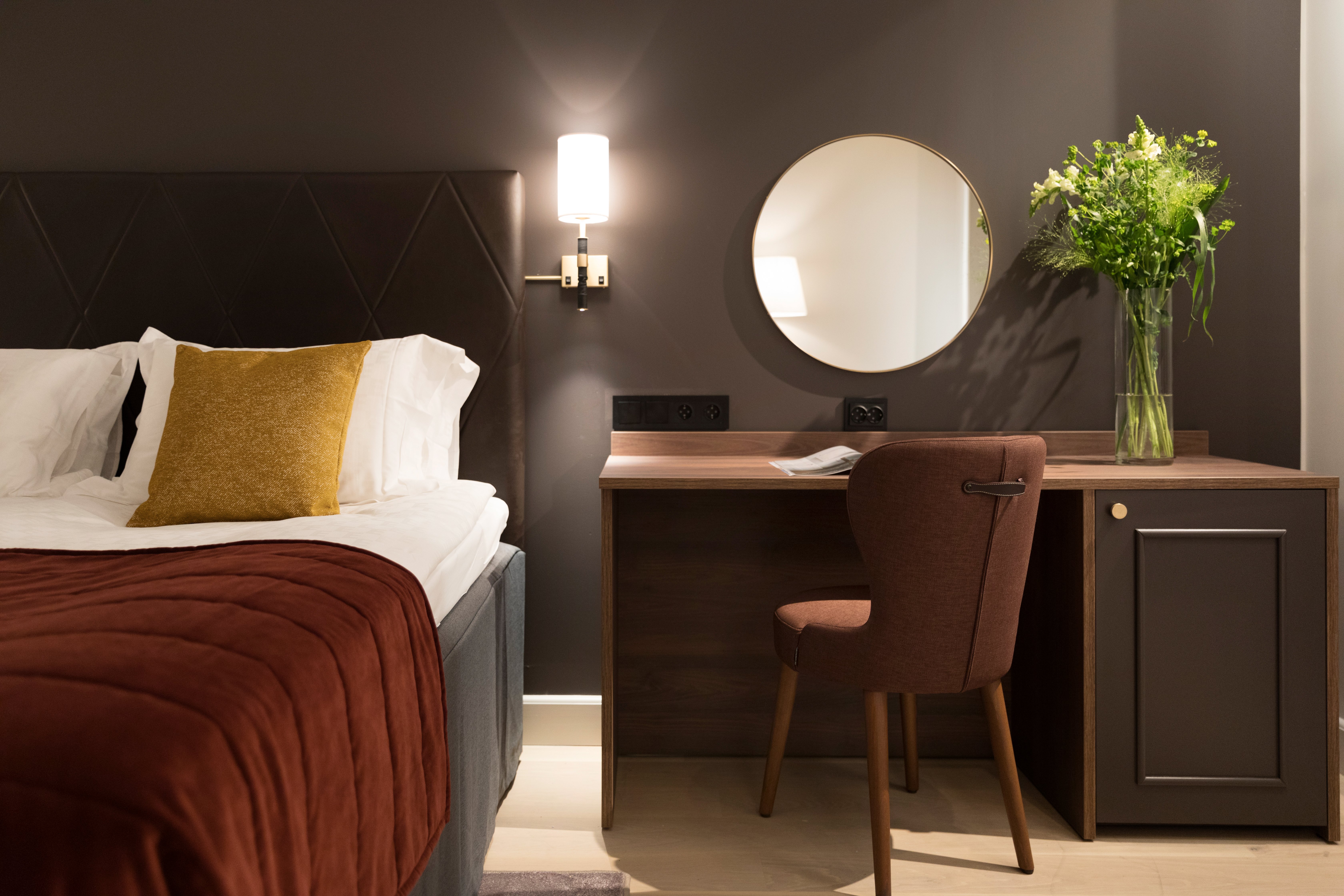 Hotellrum med säng, skrivbord och spegel