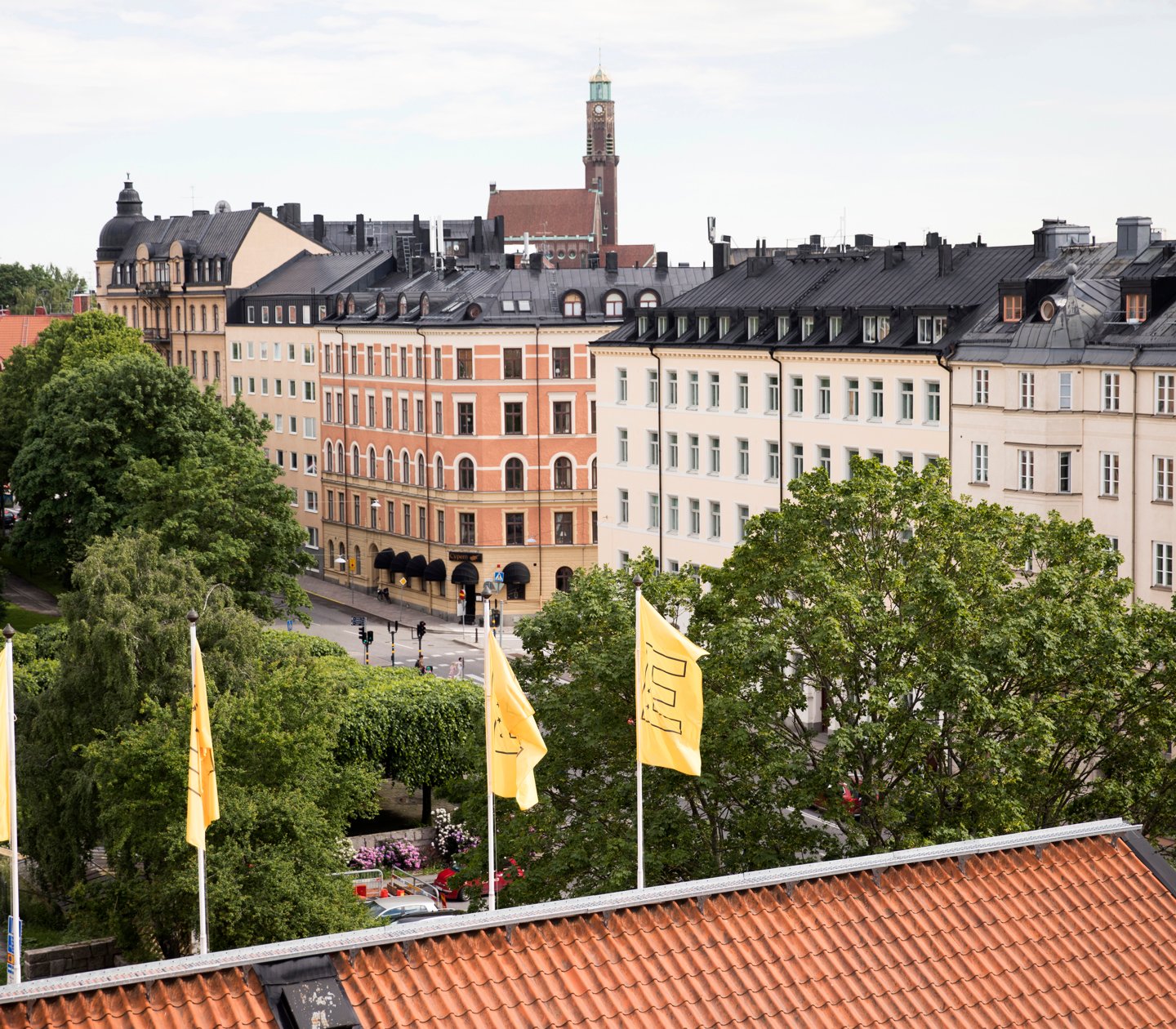 Roof of hotel and yellow Elite flags with trees in front
