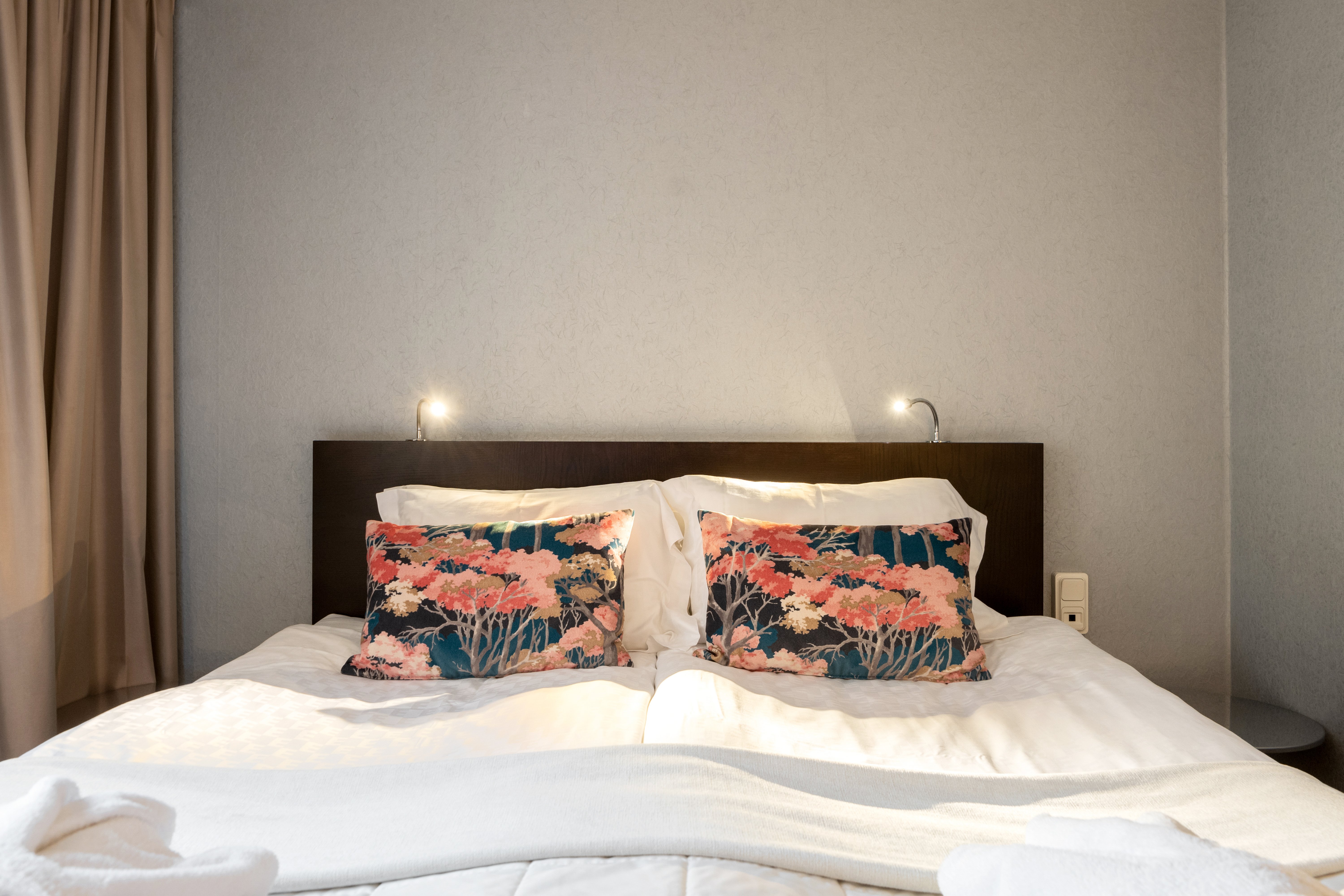 Hotellrum med dubbelsäng med blommiga kuddar och lampor