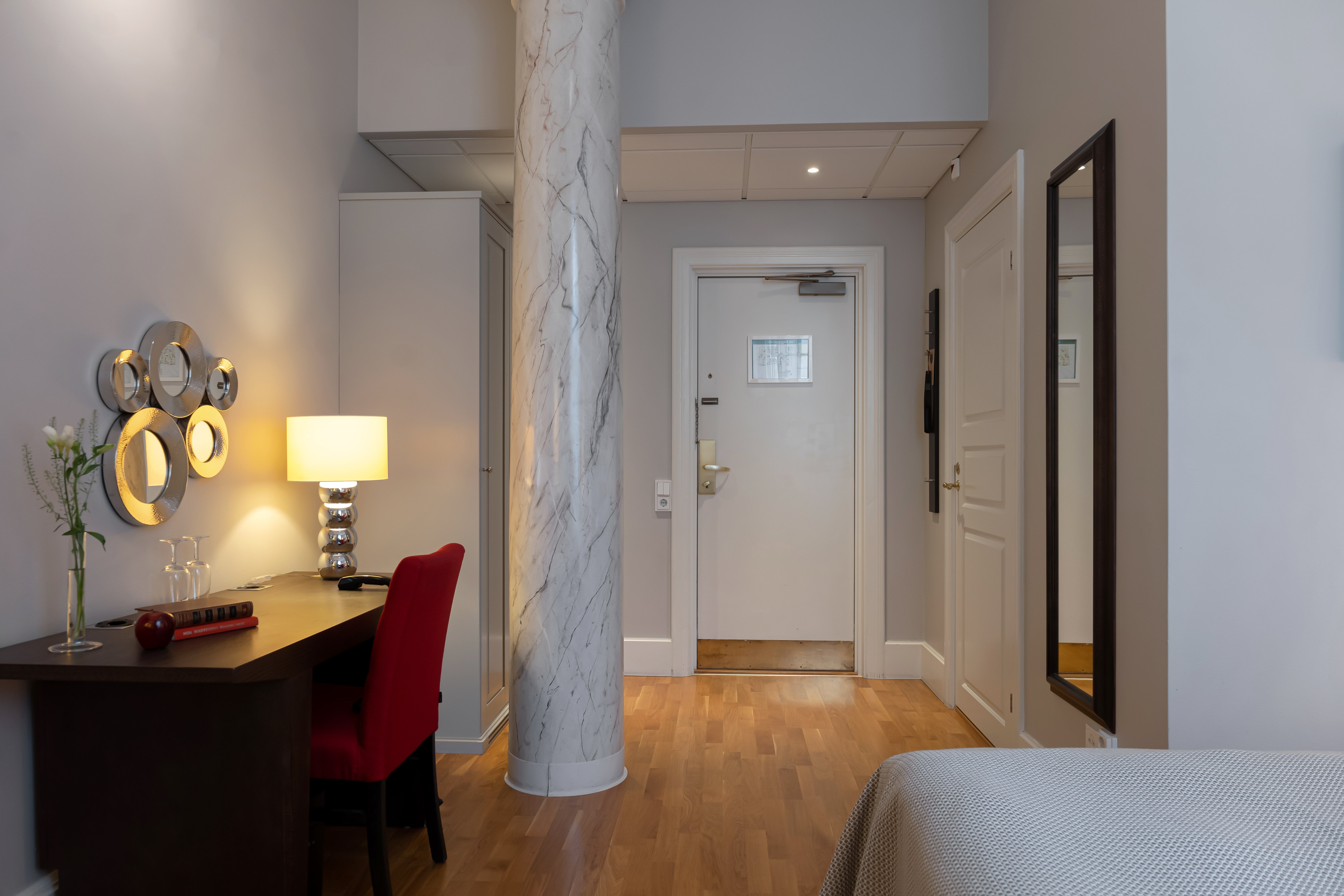 Hotellrum med pelare i marmor, skrivbord och spegel