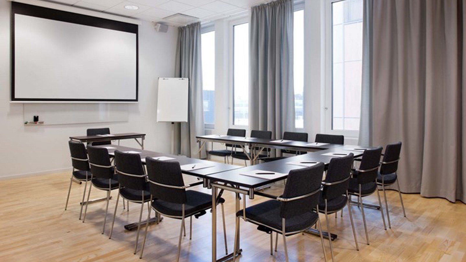 Conference room with u-shaped seating, a projector, large windows and wooden floor