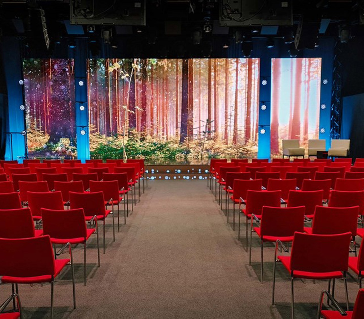 Konferenssal med biosittning, röda stolar, tv-studio, projektor