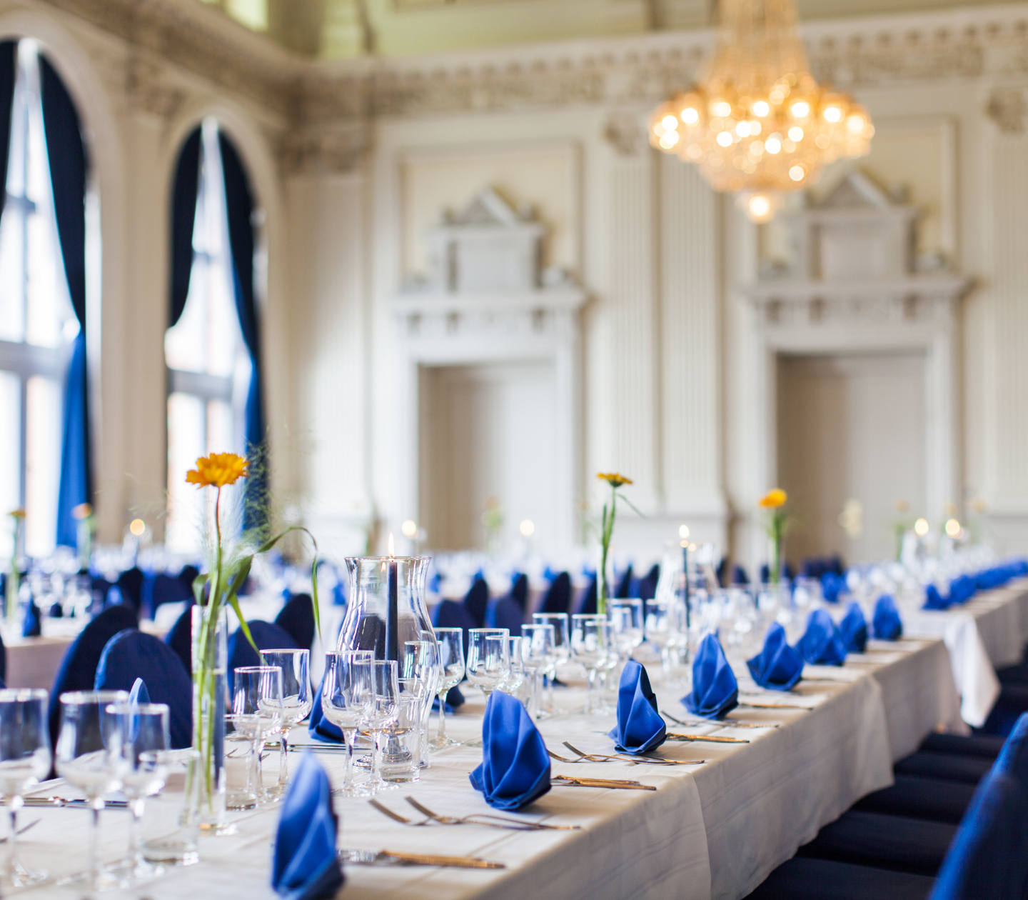 Långbord i bröllopslokal dekorerat med blå servetter