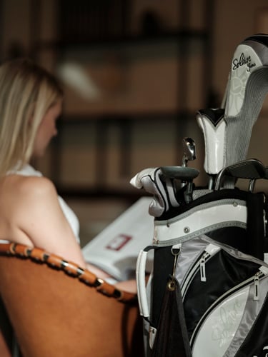 Golfbag i förgrunden och kvinna som läser tidning i bakgrunden