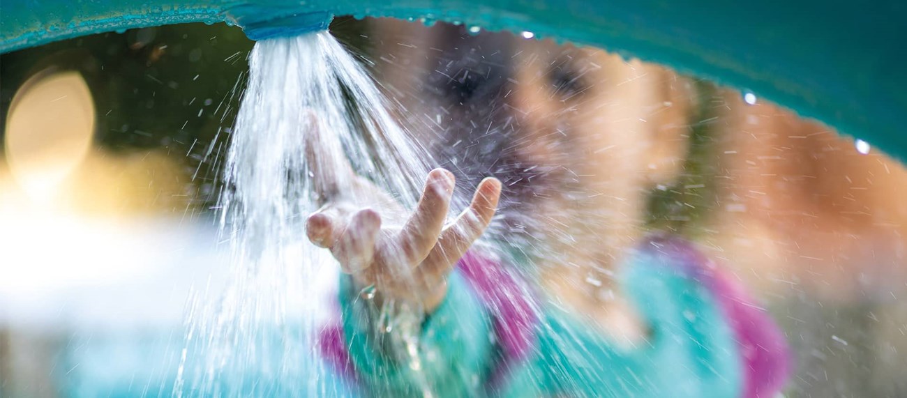 Ett barn leker med vattenstråle
