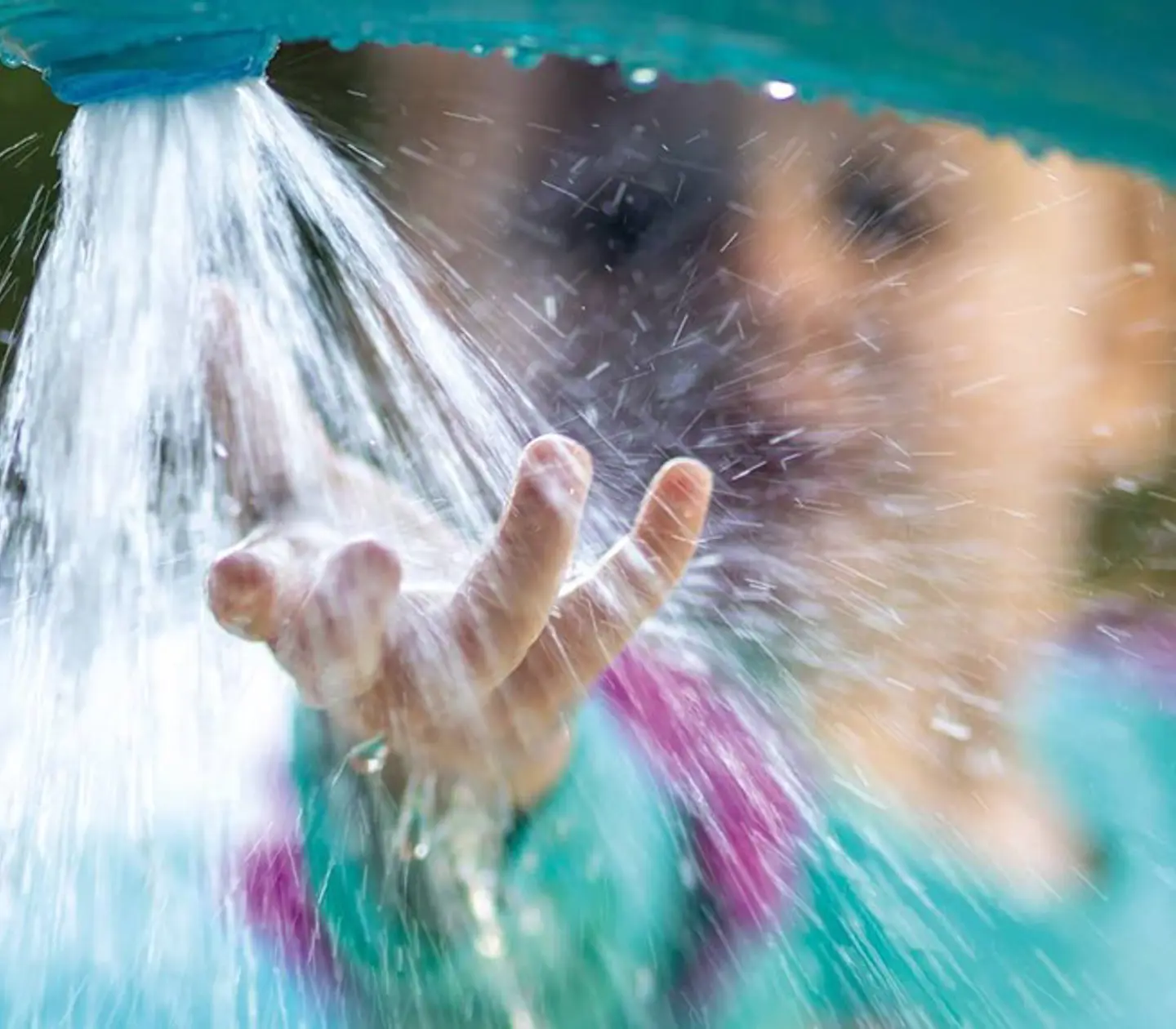 Ett barn leker med vattenstråle