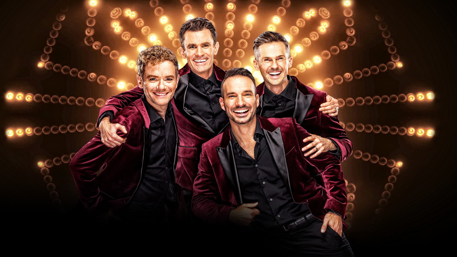 Fyra män i vinröda kavajer på scen