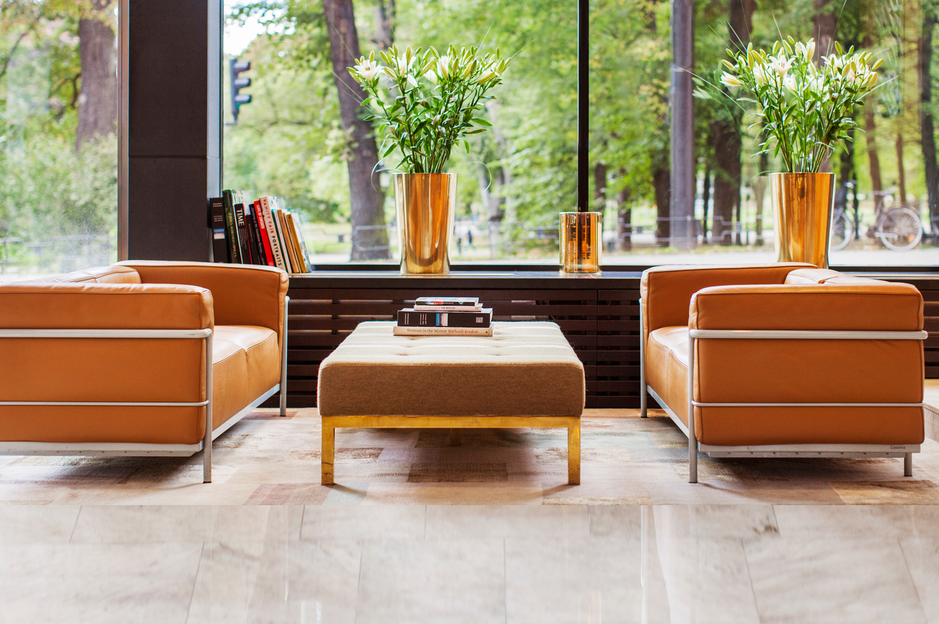 Bild på två stolar med ett bord med lite böcker längst ett fönster ut mot lite träd.