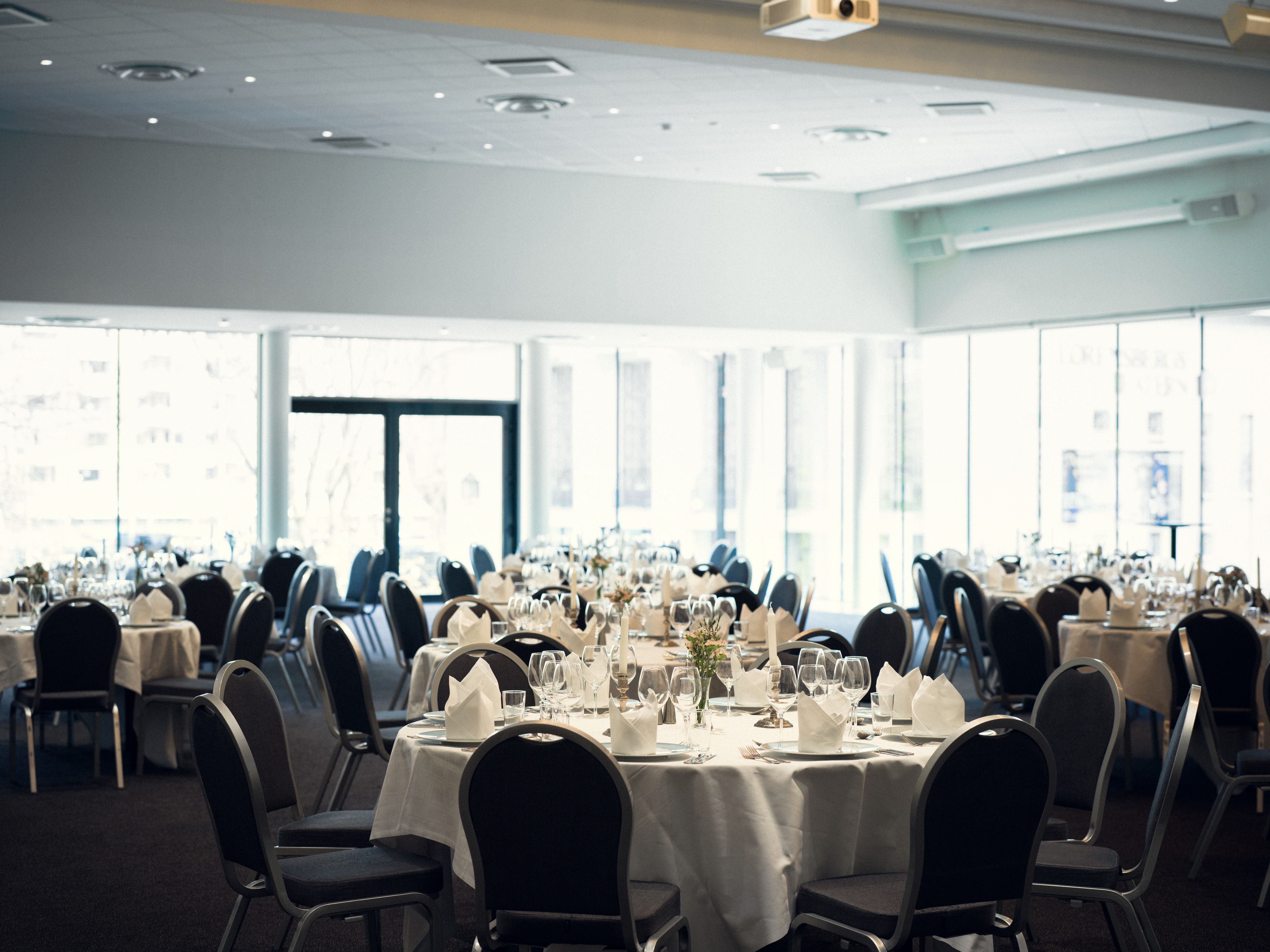 Hall with lighting in the ceiling and many round laid tables