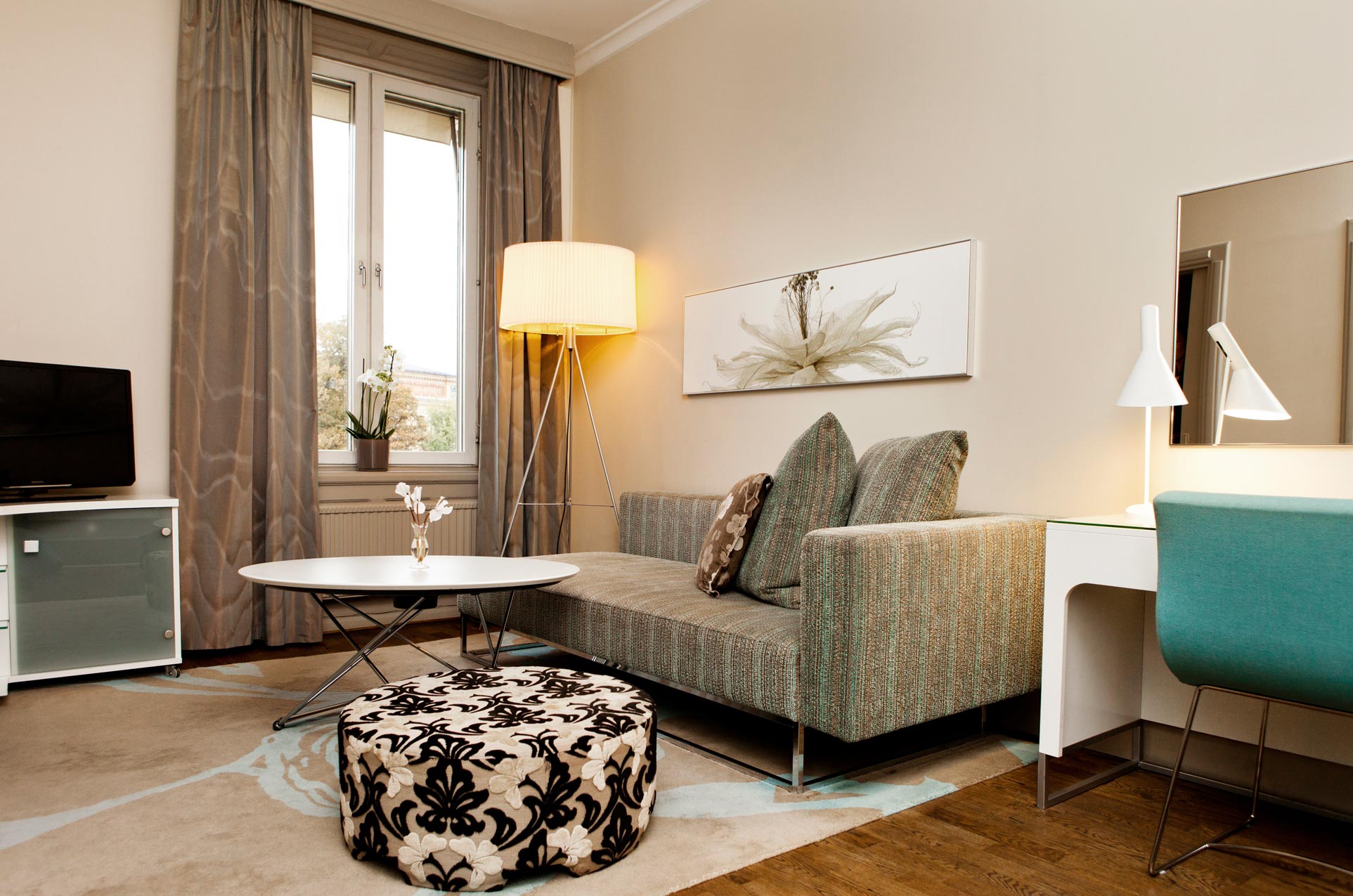 Sofa med lampa och ett bord med blomma.