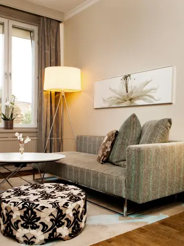 Sofa med lampa och ett bord med blomma.