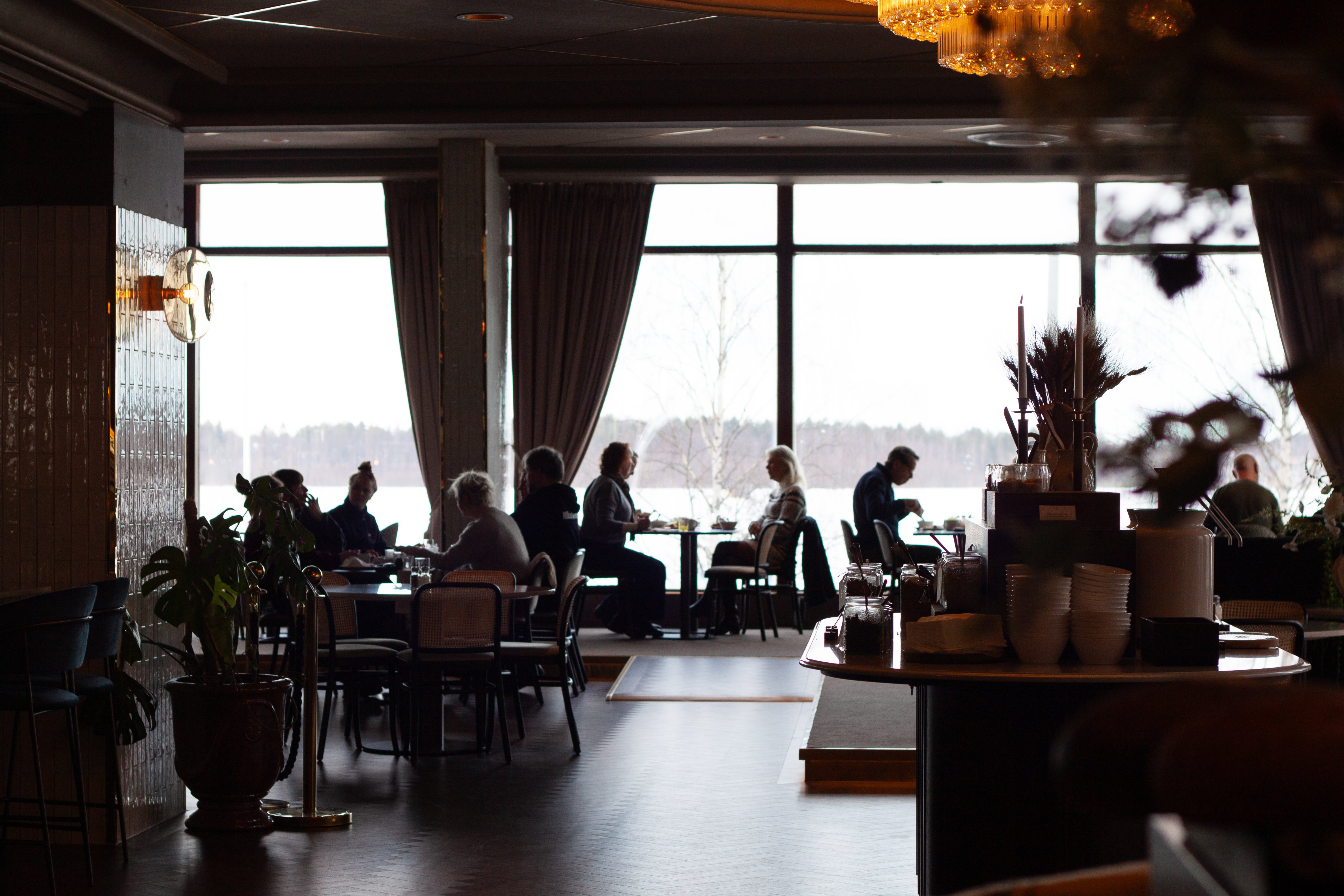 Människor sitter vid bord i en restaurang med stora fönster.