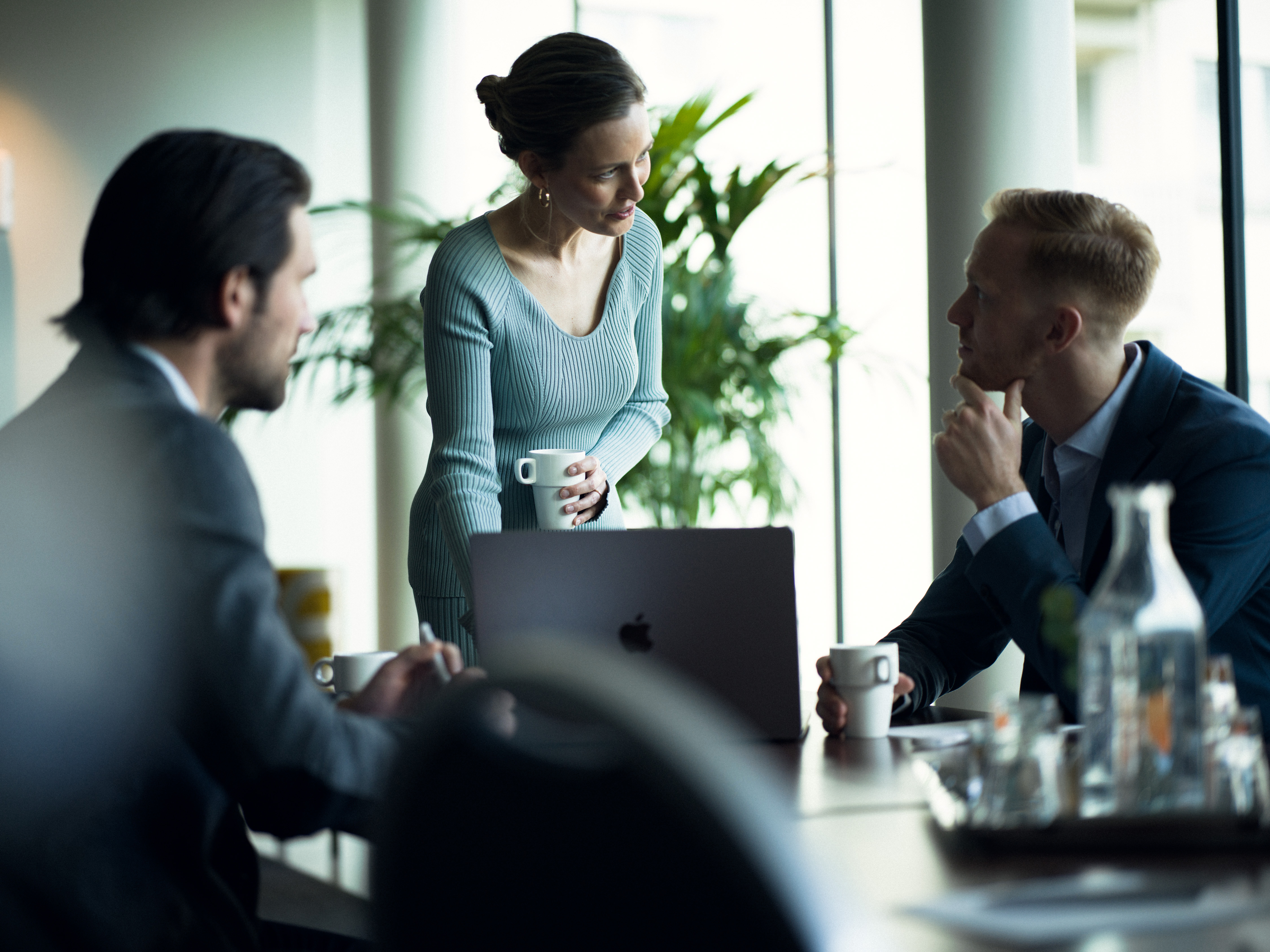 People leaning over conference table, with a computer