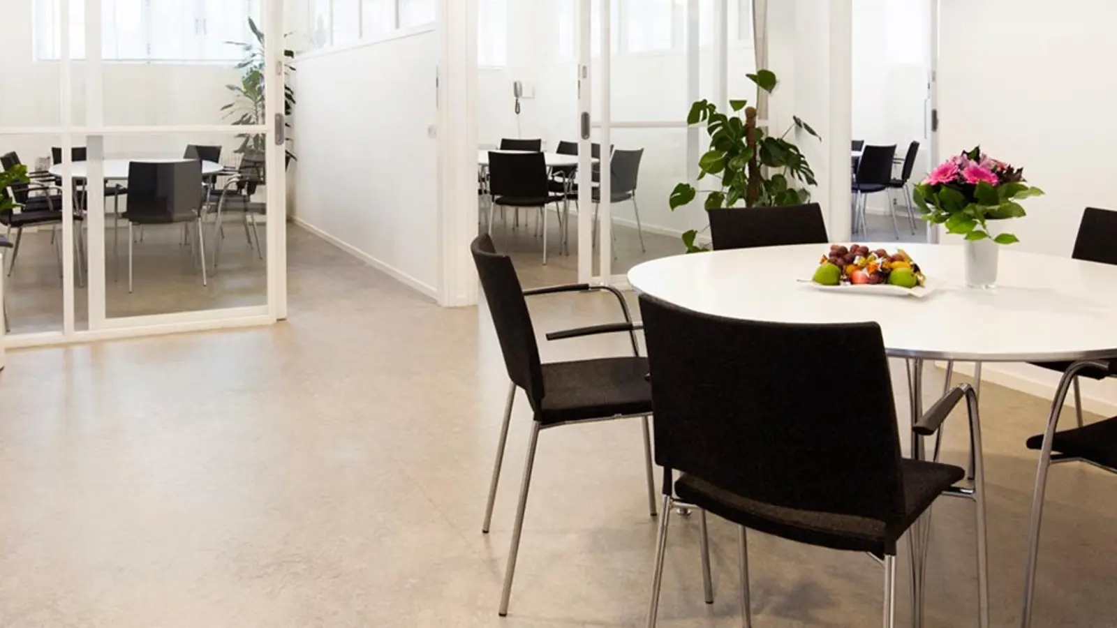 A conference table with flowers and a mirror on the wall