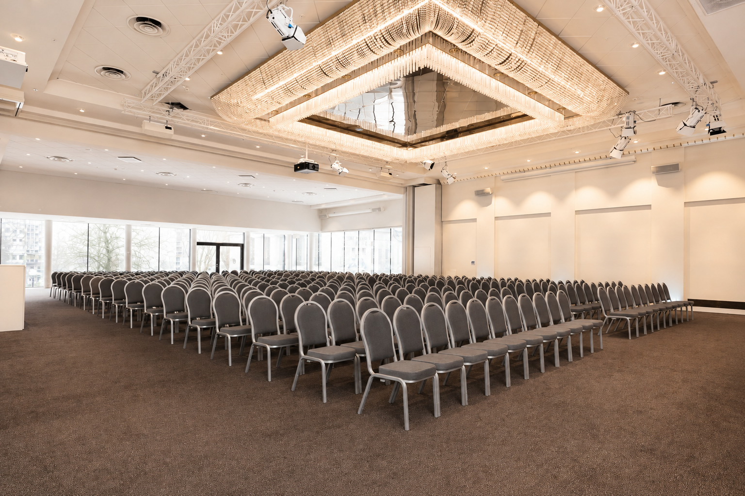Många stolar i biosittning i konferensrum med blå fyrkantig lampa