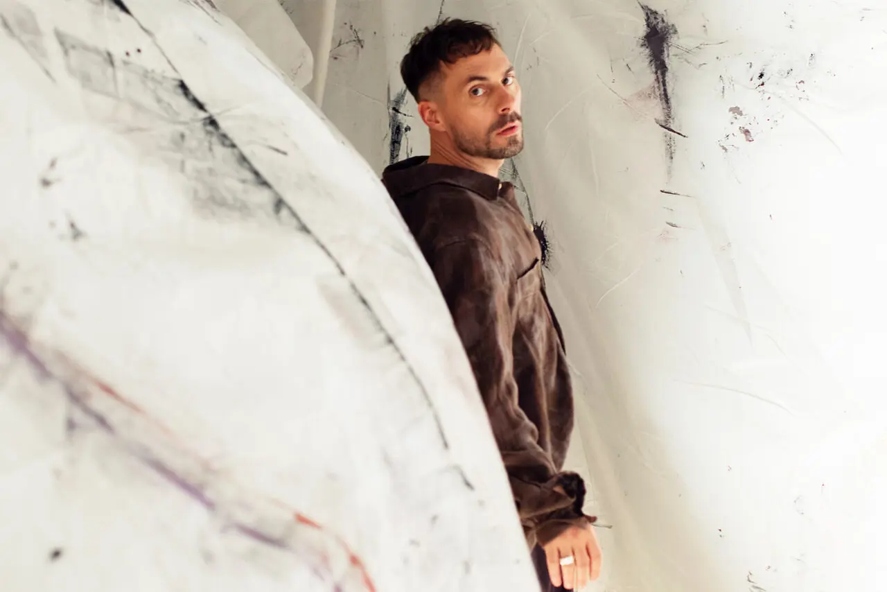 Musikensemble på scen med orkester och band, upplyst av blå scenljus under en livekonsert.