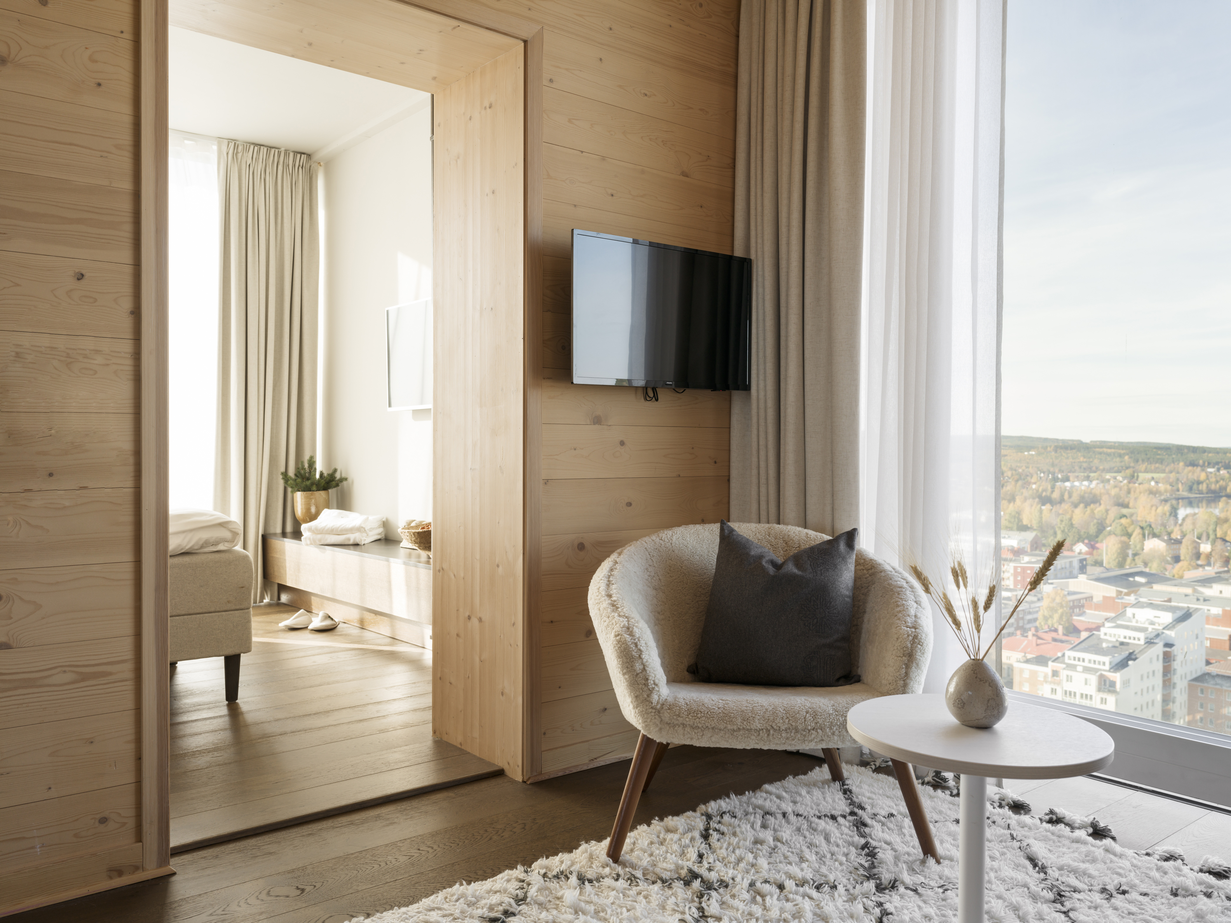 Mysigt hotellrum med soffgrupp, spegel och stort fönster