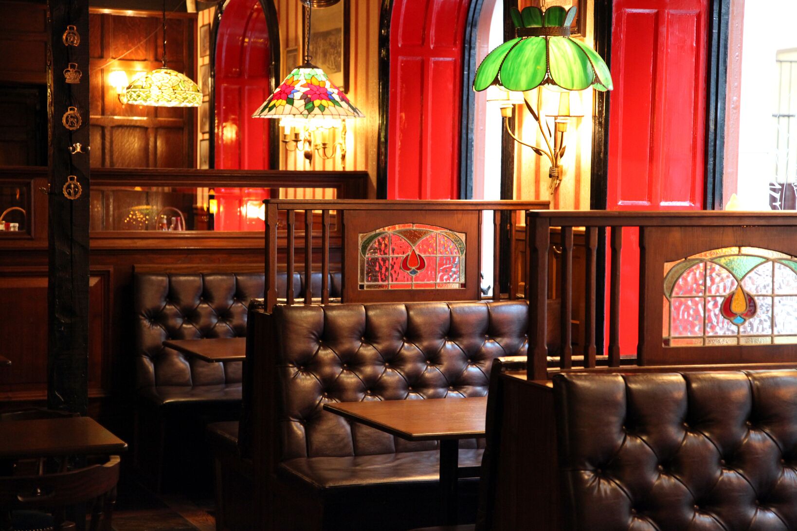 Traditionell engelsk pub med retroinredning, läderklädda sittmöbler, färgglada glasmålade lampor och mörkträdetaljer.