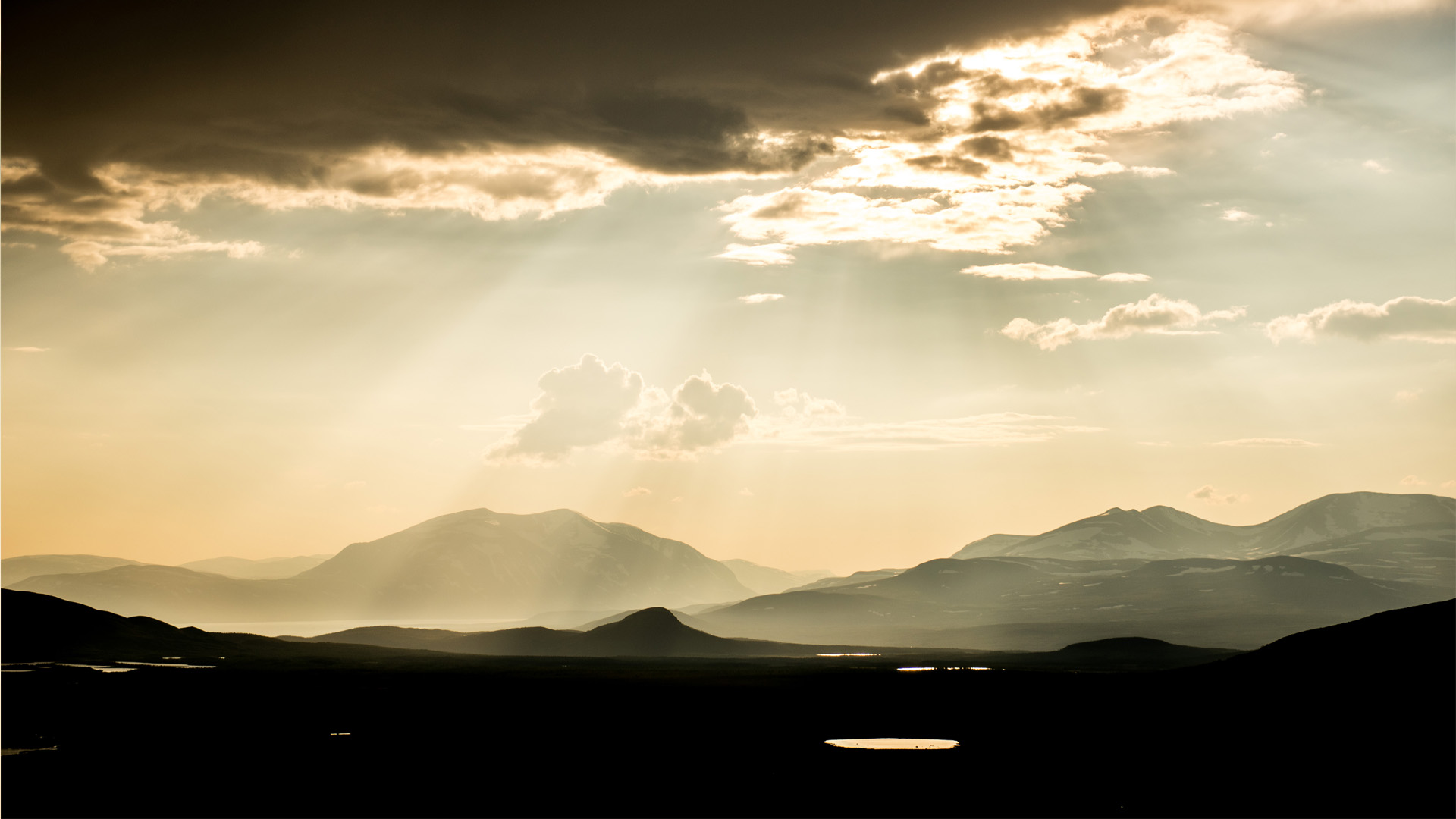 Sunlit mountains under cloudy sky