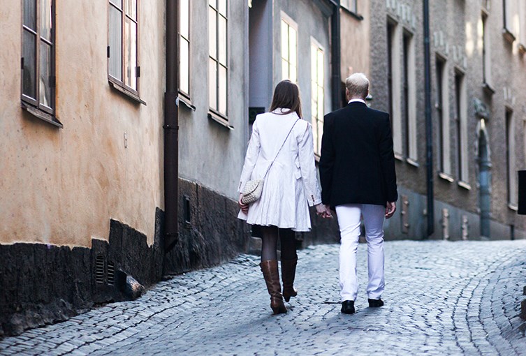 En kvinna och en man håller i handen med de går på en gata i stan