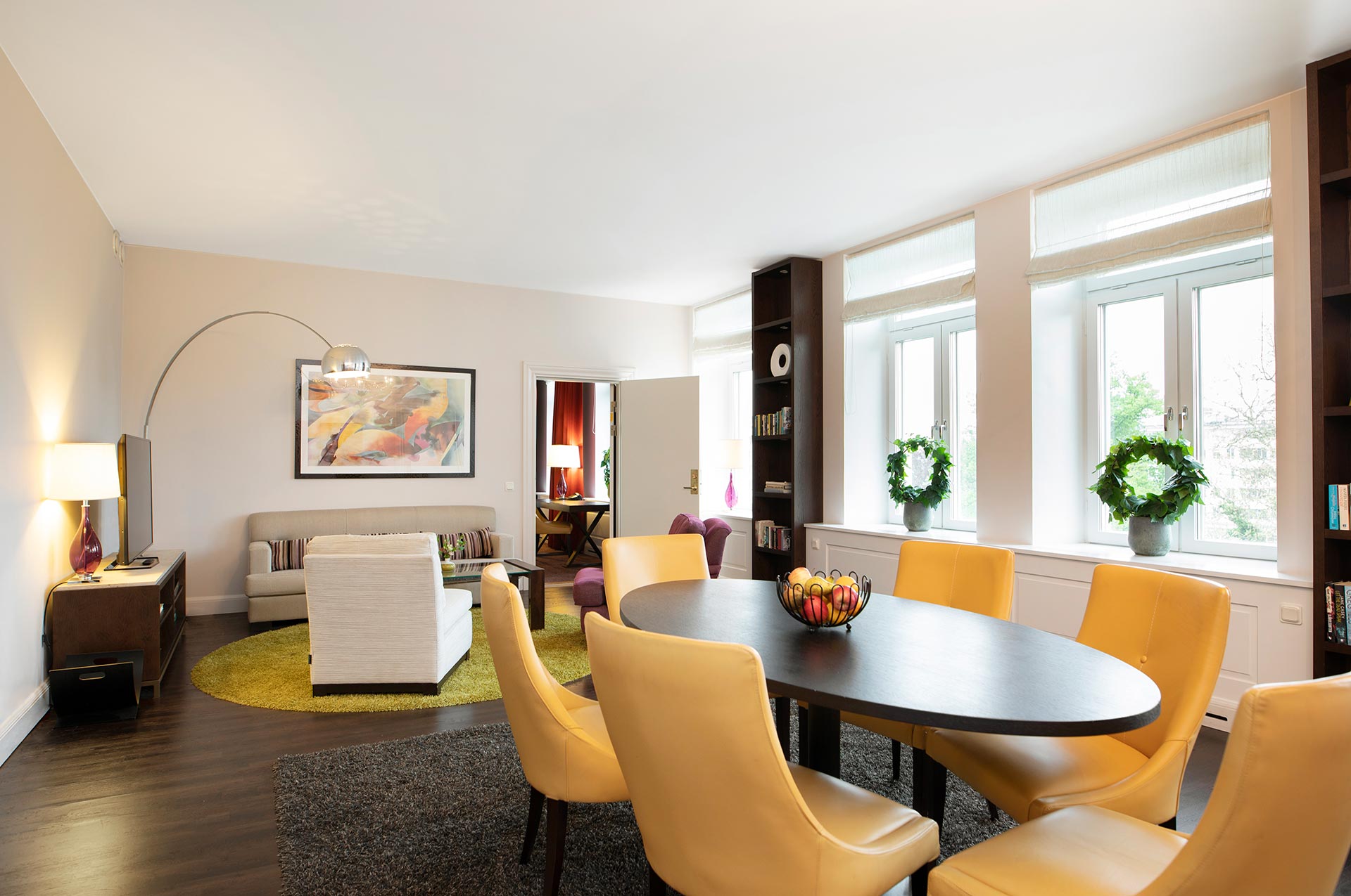 Rum med bord och gula stolar samt en soffgrupp