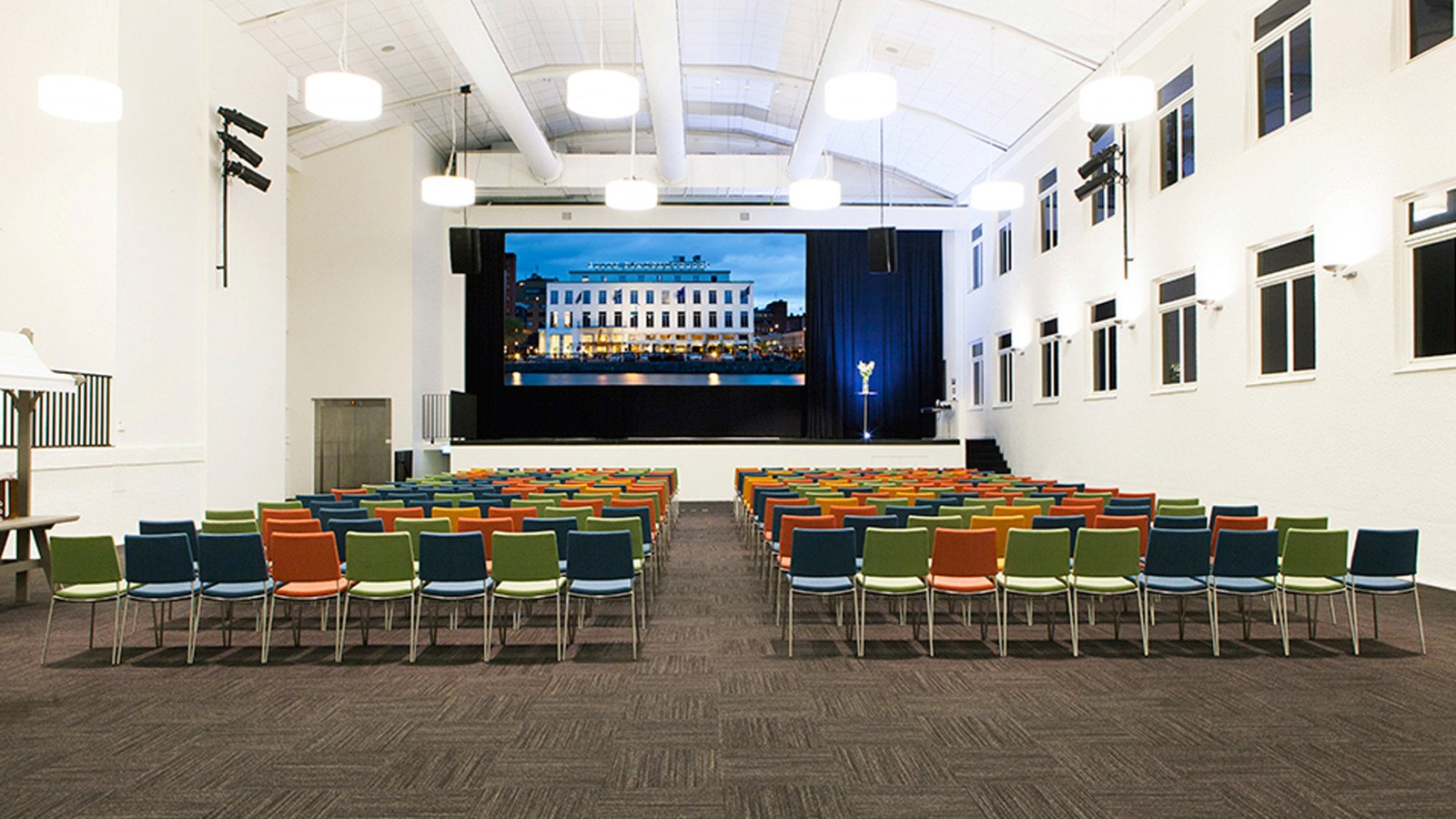 Large room with screen and many colourful chairs