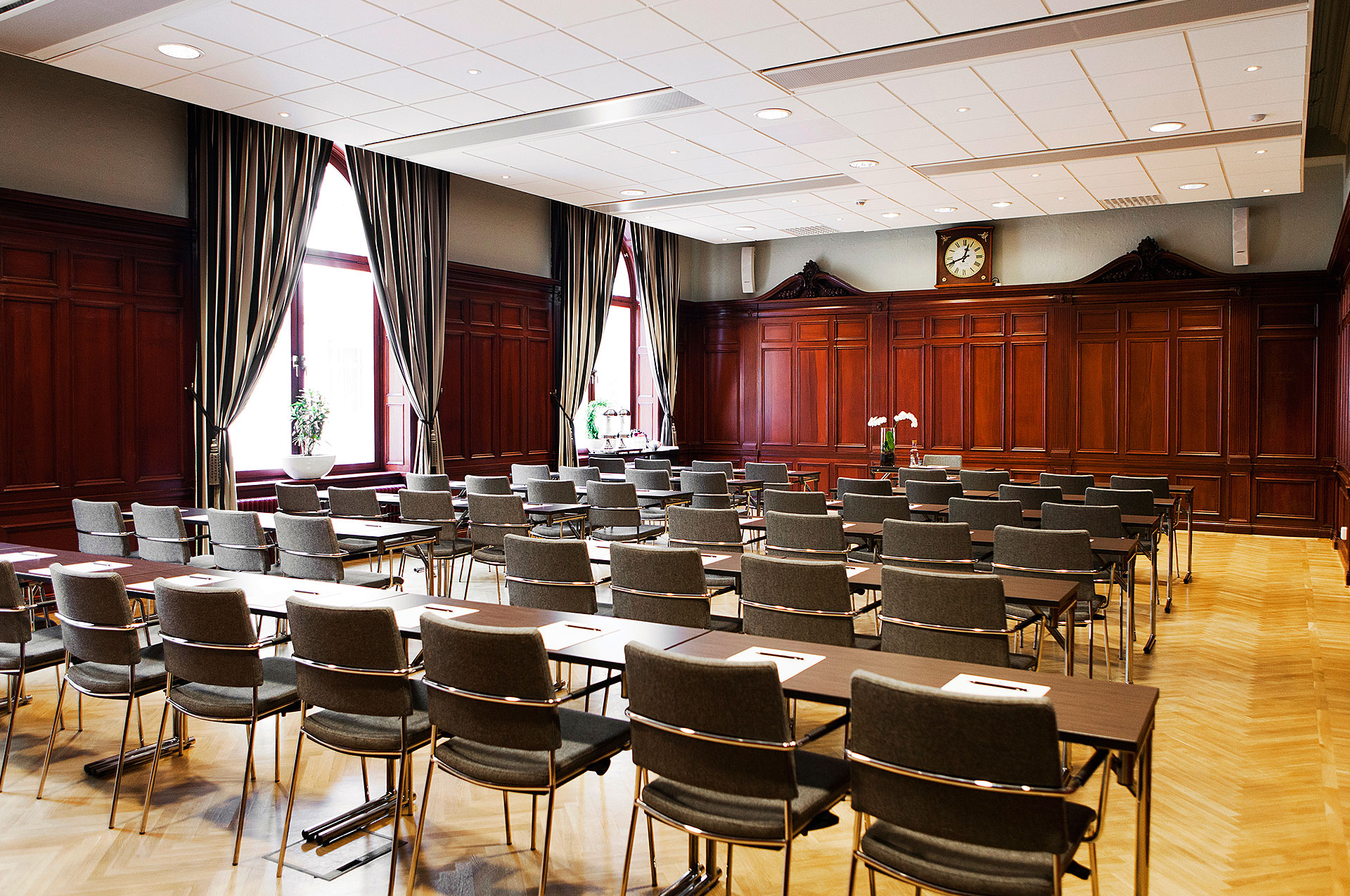 Röd konferenssal med många stolar, bord och fönster