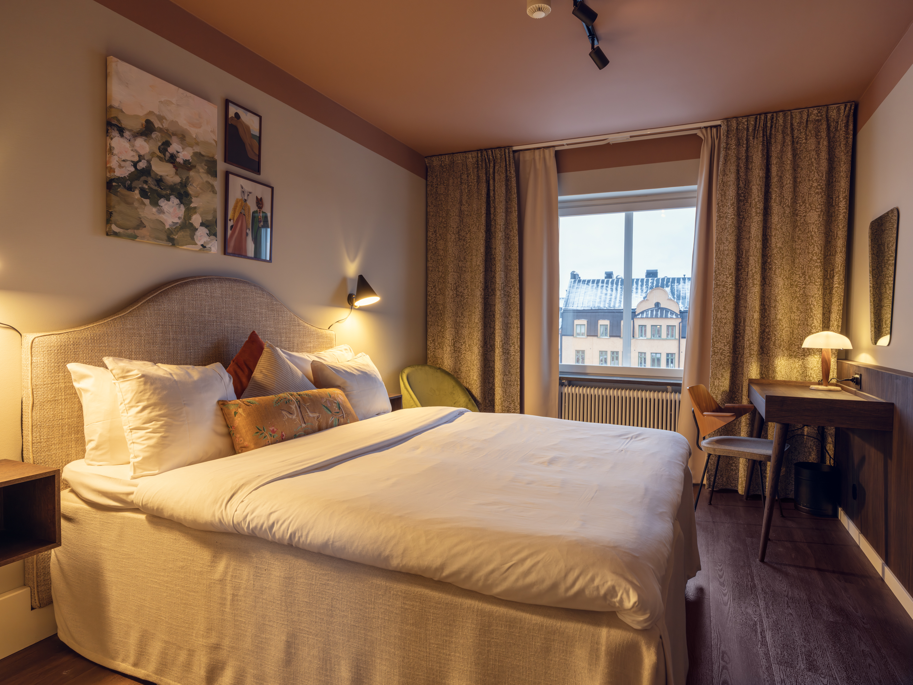 Ljust hotellrum med soffa, tv och fönster