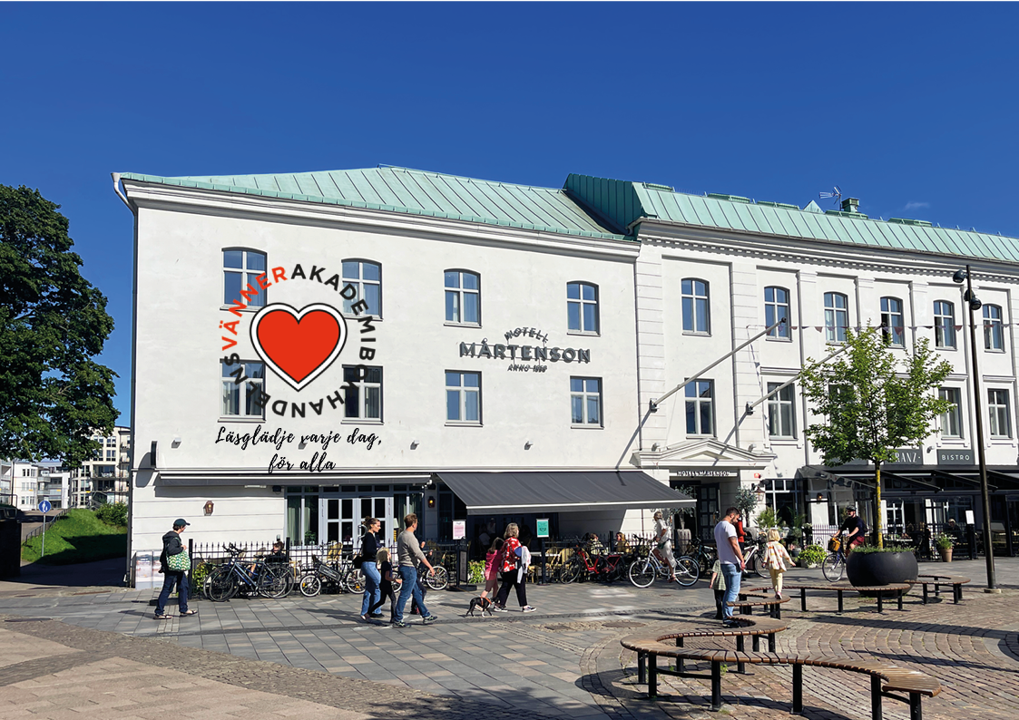 Vit byggnad med text på fasaden och cyklar utanför.