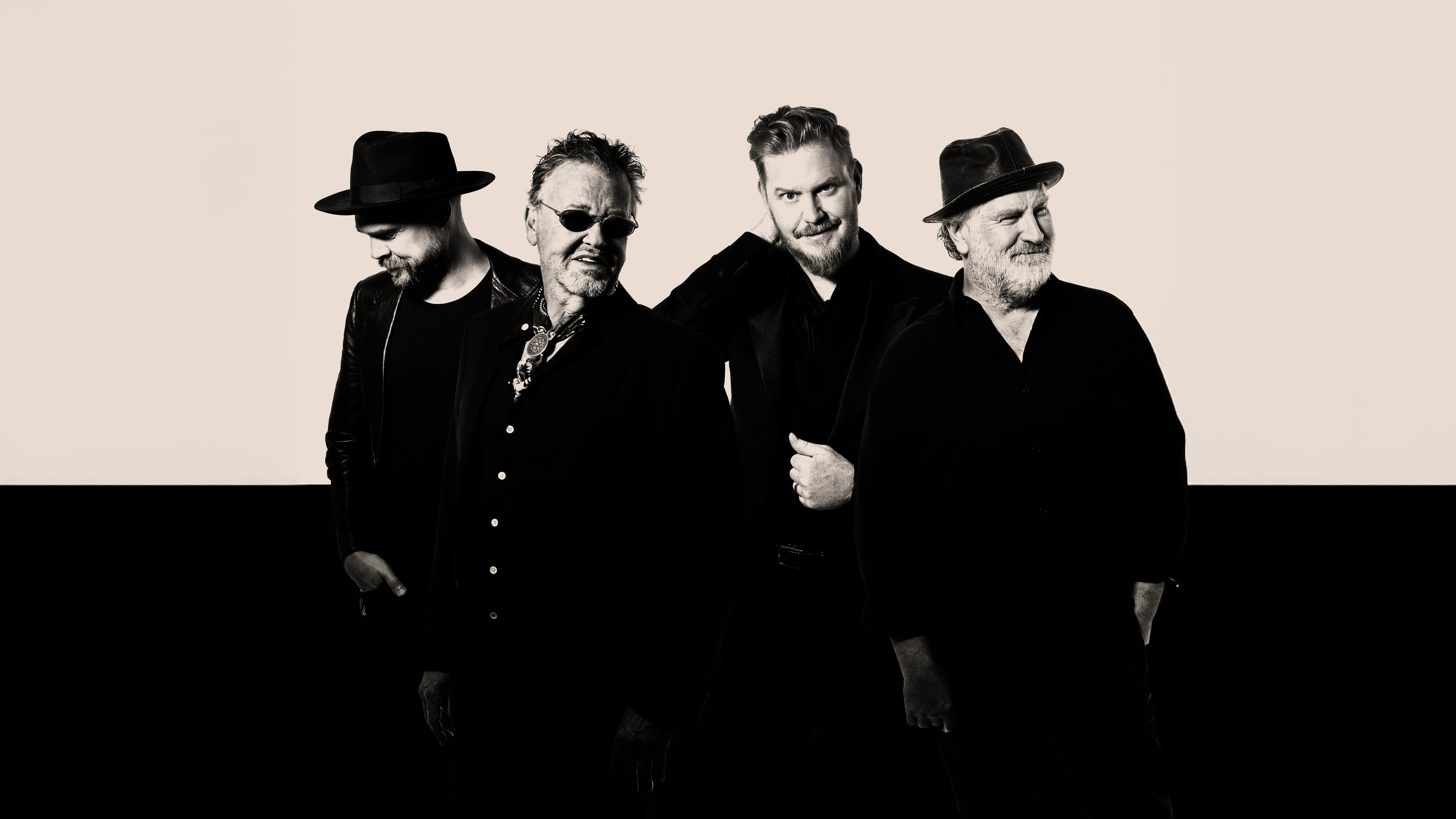 Fyra män i svarta kläder och hattar