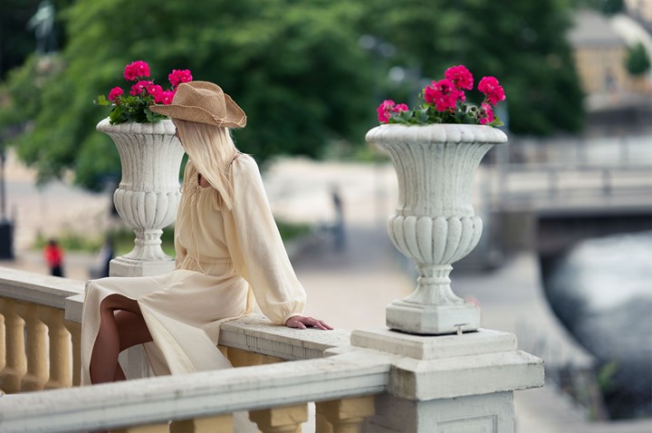En kvinna i klänning sitter på ett stenräcke