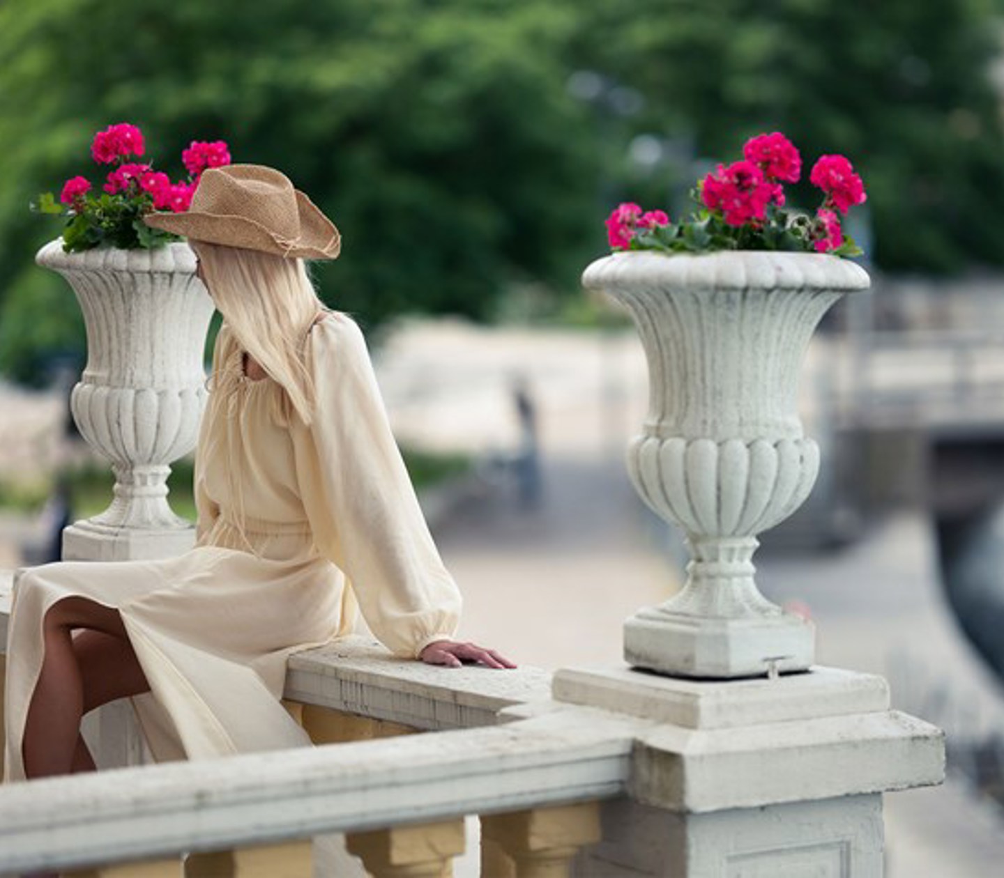 A woman in a dress sits on a stone railing