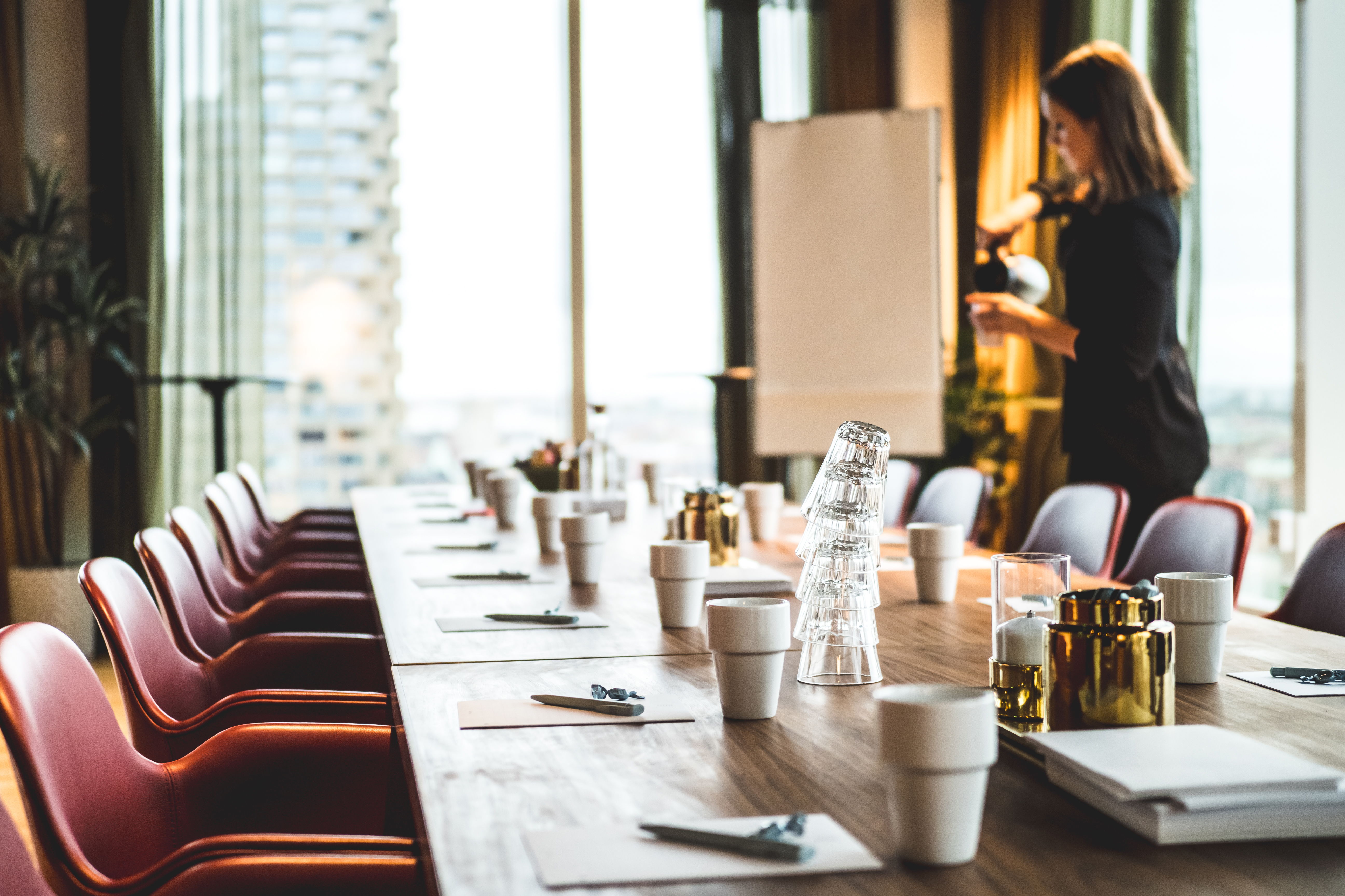 Modern dining room with gray chairs, white table, and orange curtains with natural light from window.