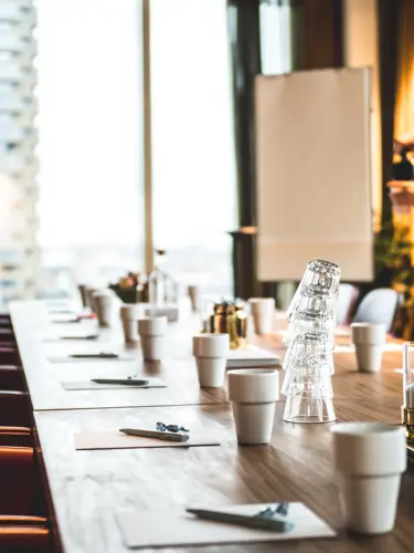 Modern dining room with gray chairs, white table, and orange curtains with natural light from window.