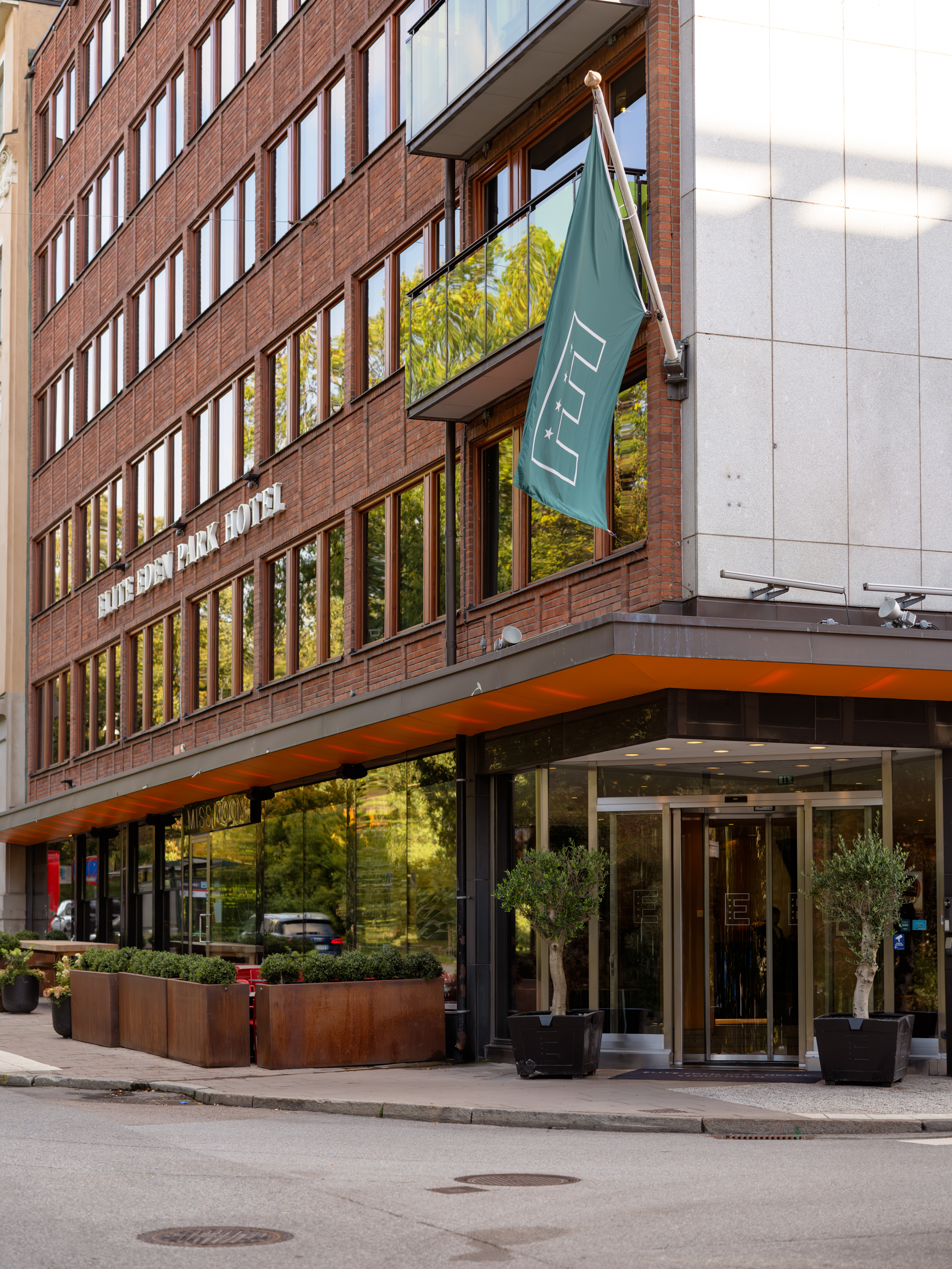 Fasaden av Elite Eden Park Hotel med träd framför