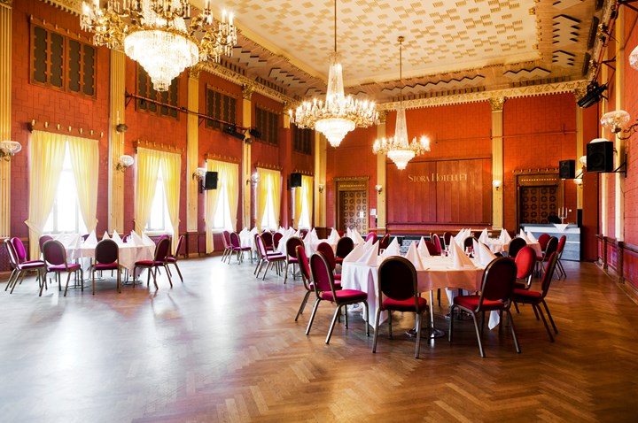 Bild på stor sal med flera matbord. 