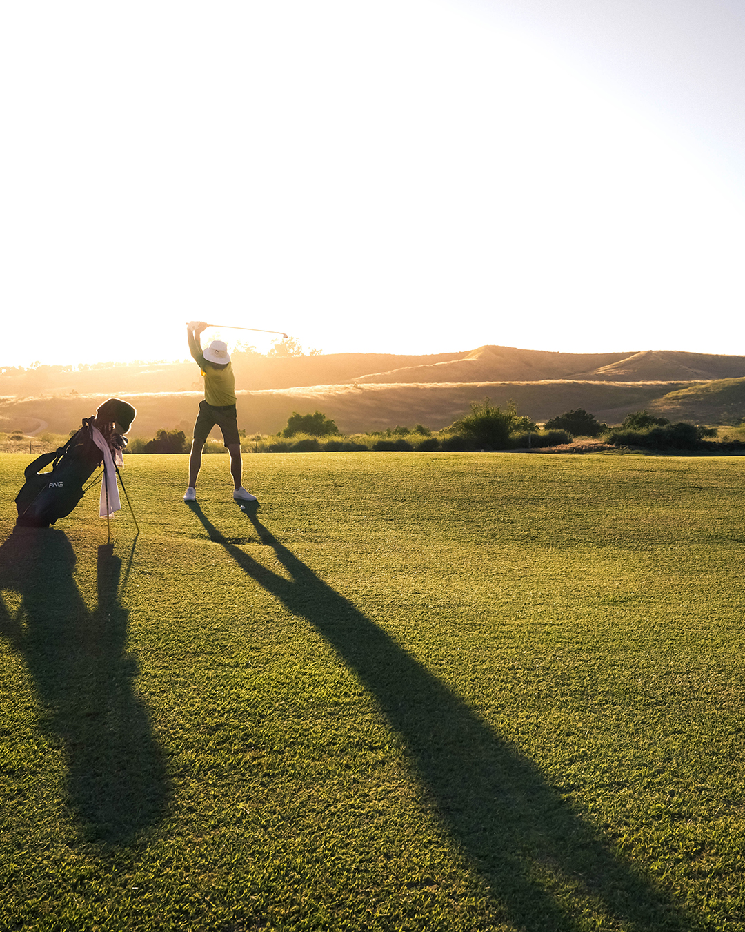 Kvinna i golfkläder lyfter upp en klubba ur en bag