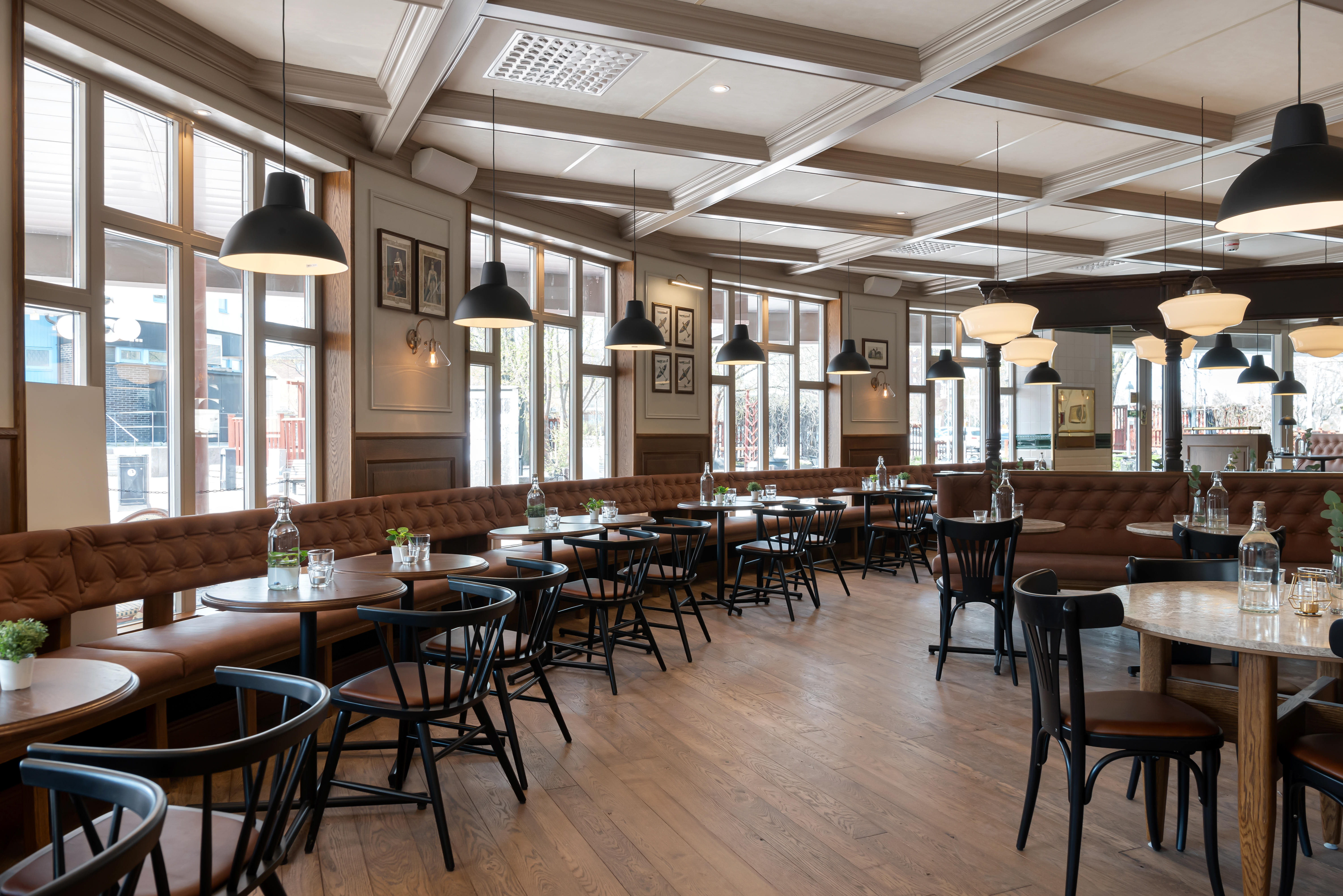 Restaurangmiljö med många bord, fönster och lampor