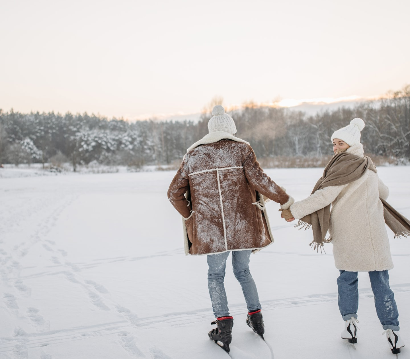 Couple holding hands and skating on lake