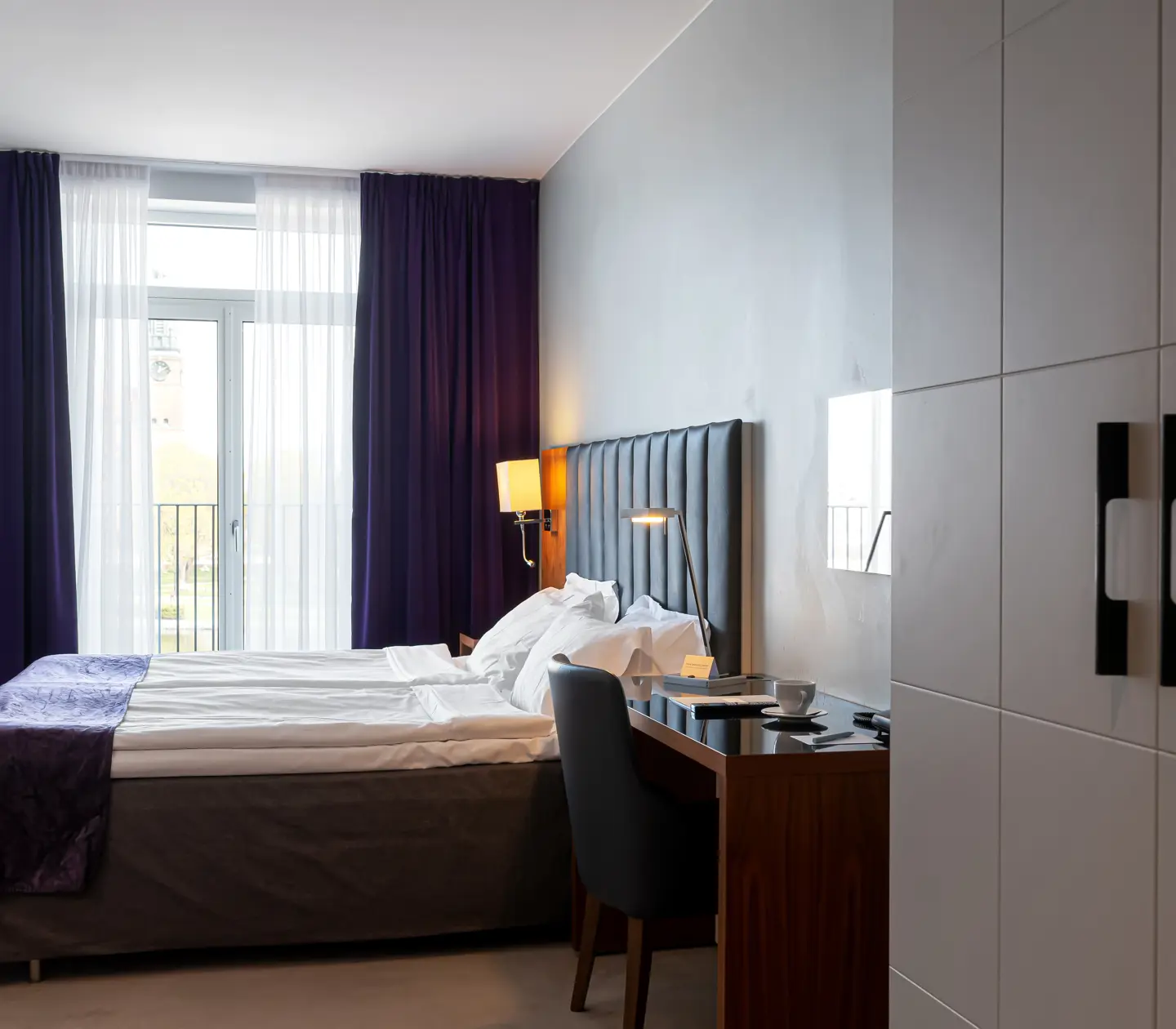 Hotellrum med dubbelsäng, skrivbord och fönster