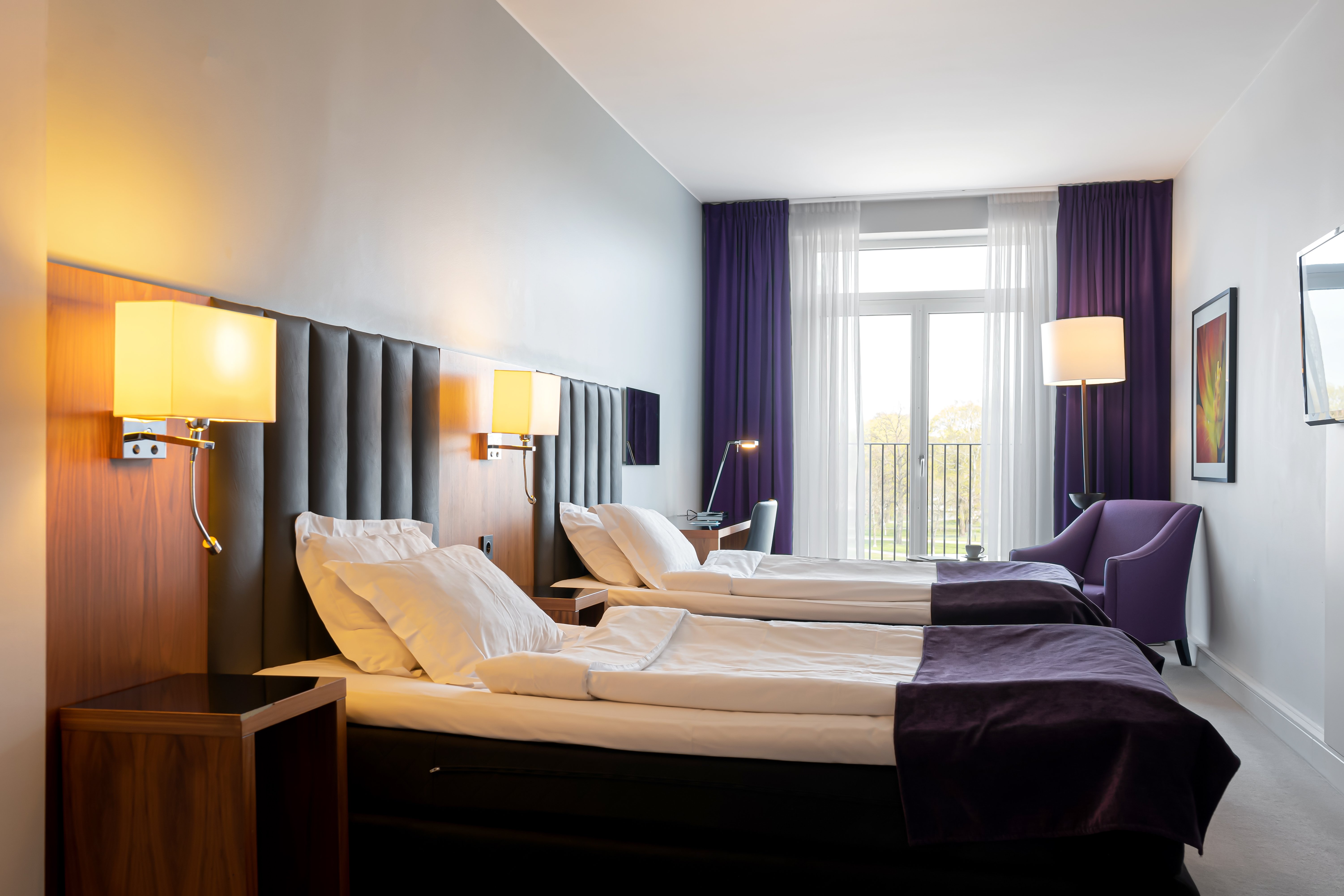 Hotel room with two single beds, armchair and desk