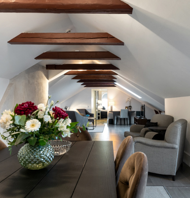 Luxurious suite with dining table, armchairs and wooden beams in the ceiling